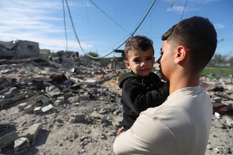 A Palestinian holds a child as they look on at the site of an Israeli strike on a house, amid the ongoing conflict between Israel and the Palestinian Islamist group Hamas, in Rafah, in the southern Gaza Strip, Saturday.