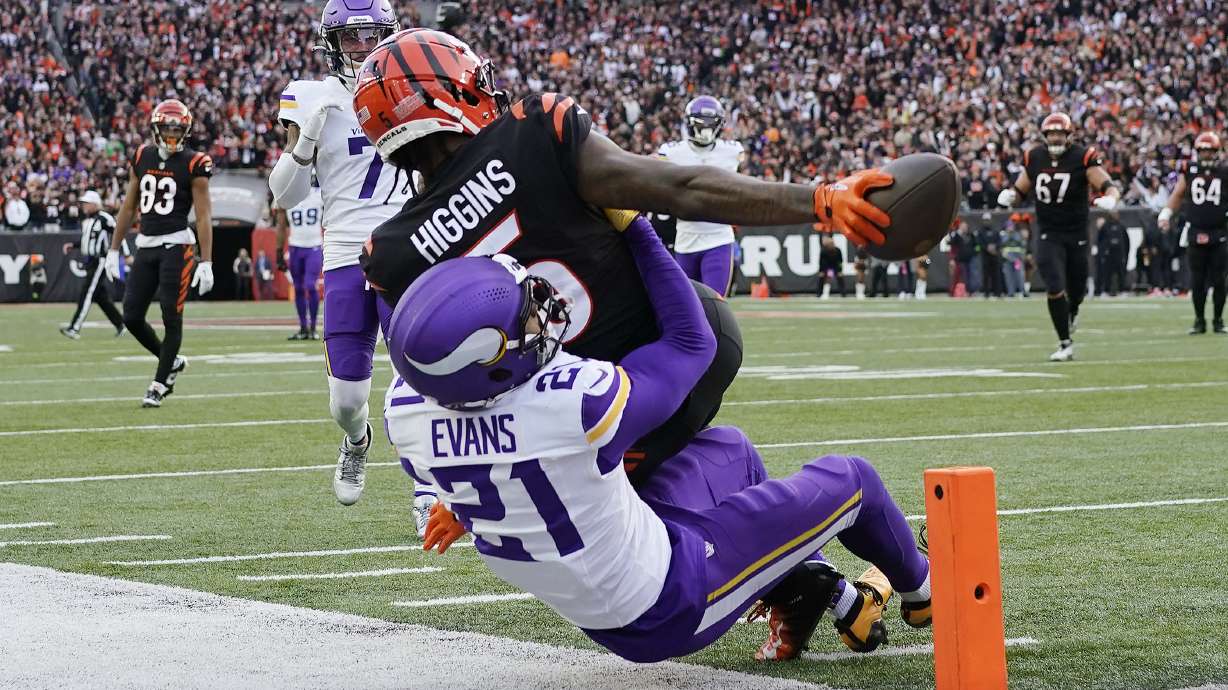 Cincinnati Bengals wide receiver Tee Higgins (5) reaches for the end zone to score a touchdown over Minnesota Vikings cornerback Akayleb Evans (21) of an NFL football game Saturday, Dec. 16, 2023, in Cincinnati.