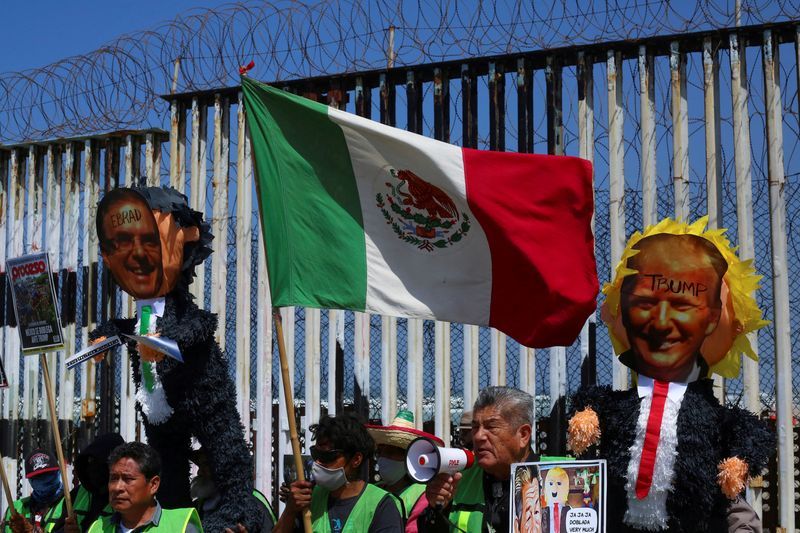 People hold up pinatas with pictures of Mexican Foreign Minister Marcelo Ebrard and former President Donald Trump during a protest at the border fence in Playas Tijuana, Mexico April 29, 2022.