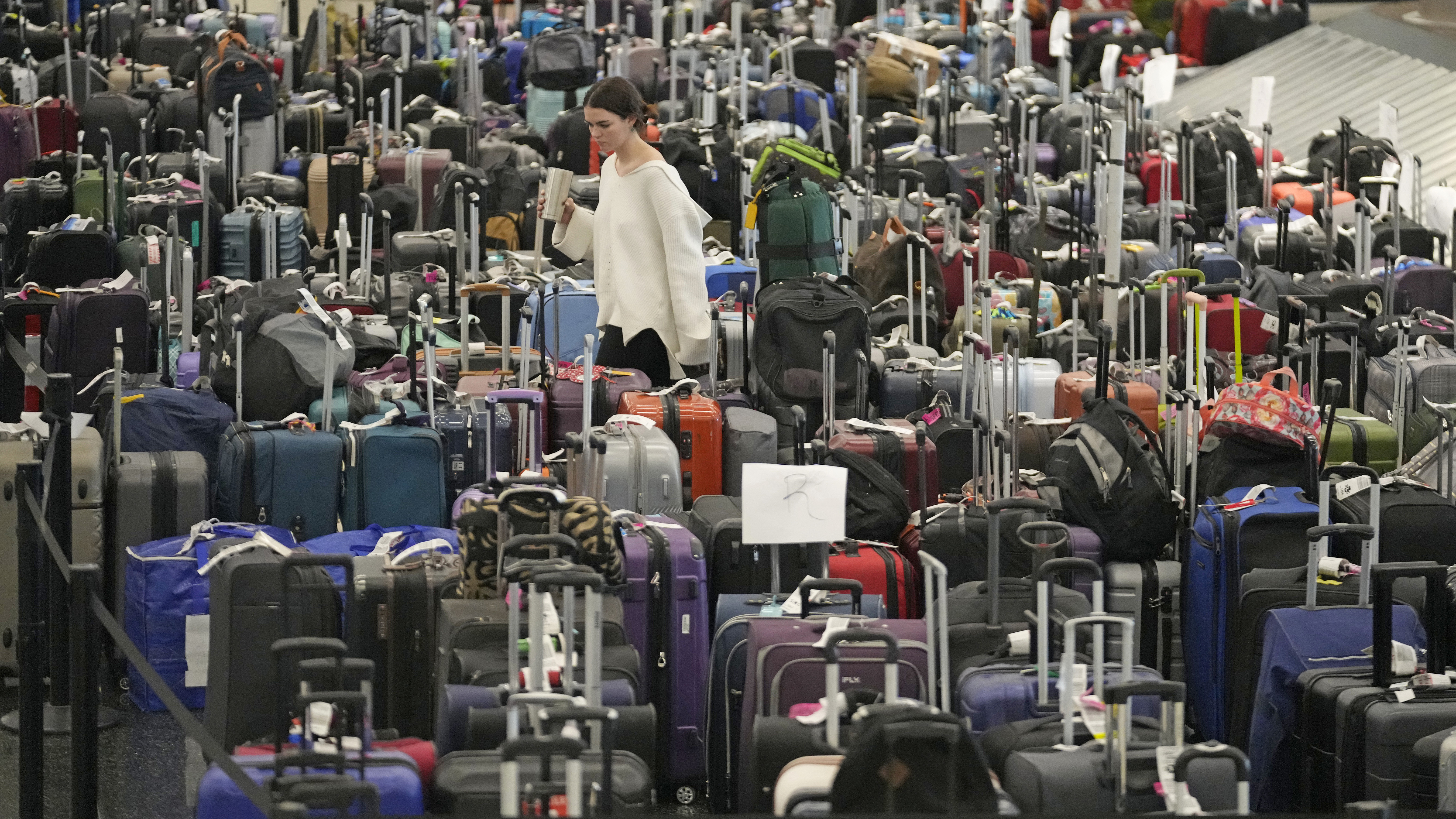 A woman walks through unclaimed bags at Southwest Airlines baggage claim at Salt Lake City International Airport on Dec. 29, 2022. Southwest Airlines will pay a $35 million fine as part of a $140 million agreement to settle a federal investigation into a debacle last December when the airline canceled thousands of flights and stranded more than 2 million travelers over the holidays.