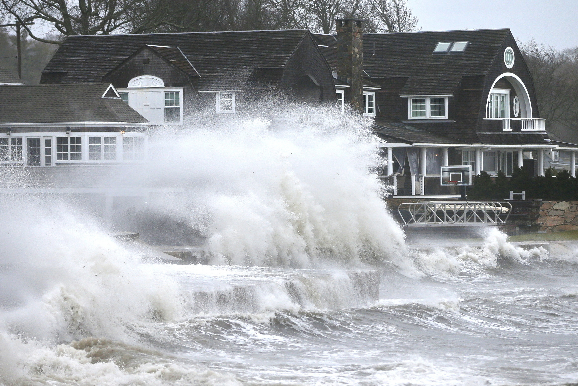 High winds drive surf into a retaining wall in front of a residence in Mattapoisett, Mass. on Monday, as a storm makes its away across the region.
