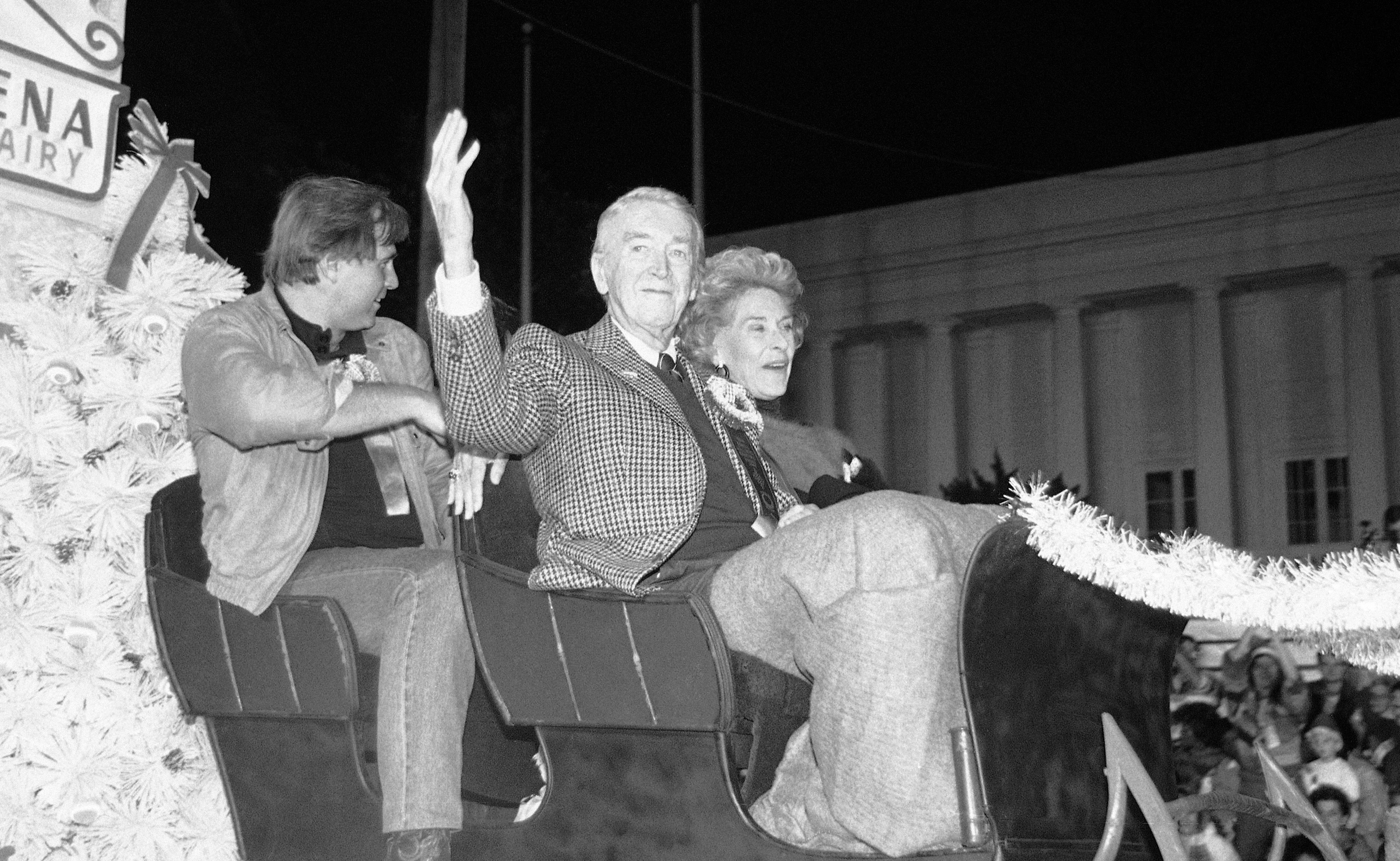 Actor Jimmy Stewart waves as he rides down Sunset Boulevard in the annual Christmas parade in Hollywood, Los Angeles on Nov. 30, 1986. At right is Stewart’s wife, Gloria, and left is actor Gil Gerald.