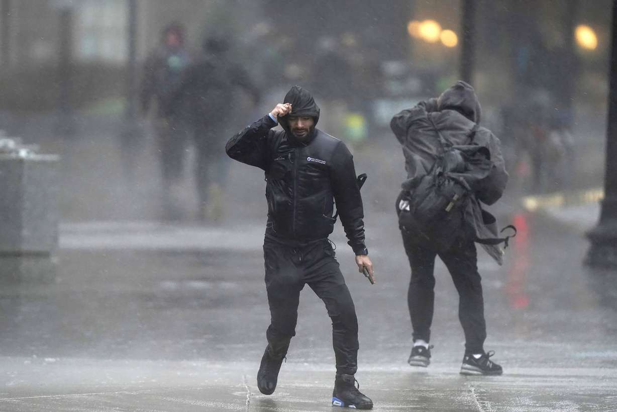 Pedestrians are buffeted by wind and rain as they cross a street, Monday, in Boston. A storm moving up the East Coast brought heavy rain and high winds to the Northeast on Monday, threatening flooding, knocking out power to hundreds of thousands.