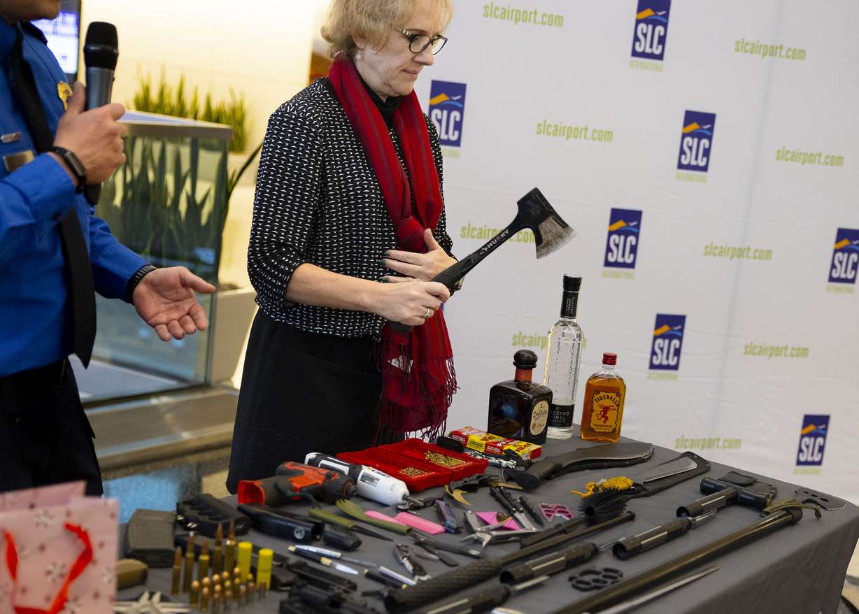 Lorie Dankers, with TSA public affairs, displays a table full of weapons, bottles and other items that the Transportation Security Administration had to take from passengers in recent weeks at Salt Lake City International Airport on Monday.