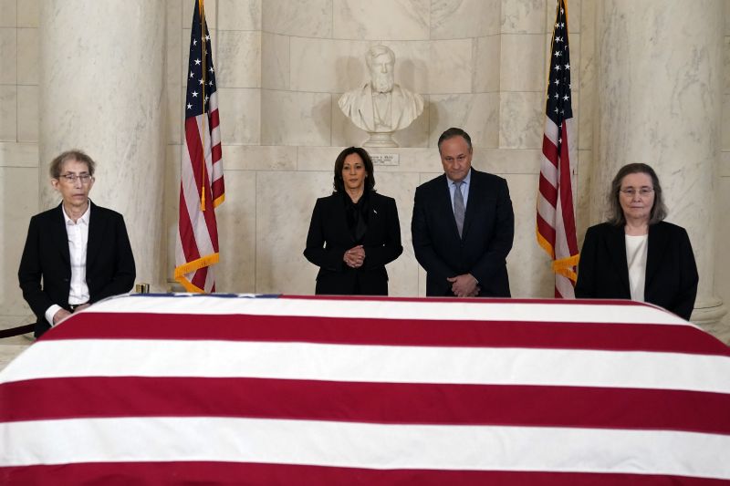 Vice President Kamala Harris and second gentleman Doug Emhoff pause in front of the flag-draped casket of retired Supreme Court Justice Sandra Day O'Connor in the Great Hall at the Supreme Court in Washington, Monday. Former law clerks of O'Connor stand at left and right.