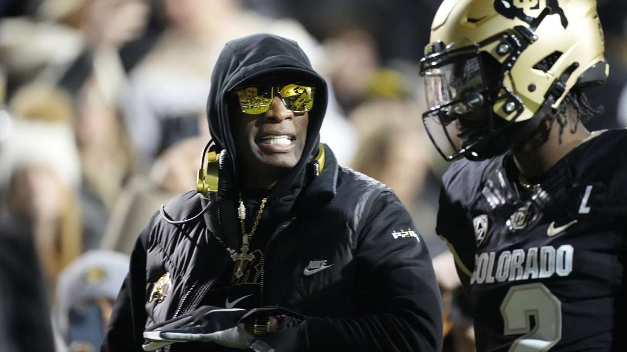 FILE - Colorado head coach Deion Sanders, left, talks to his son, quarterback Shedeur Sanders, in the first half of an NCAA college football game against Stanford Friday, Oct. 13, 2023, in Boulder, Colo. Deion Sanders is accomplishing what he pledged to do by overhauling his offensive line to better protect his often-hit quarterback son. The Colorado coach reached into the transfer portal and brought in linemen from the University of Houston, Connecticut, Indiana and UTEP.