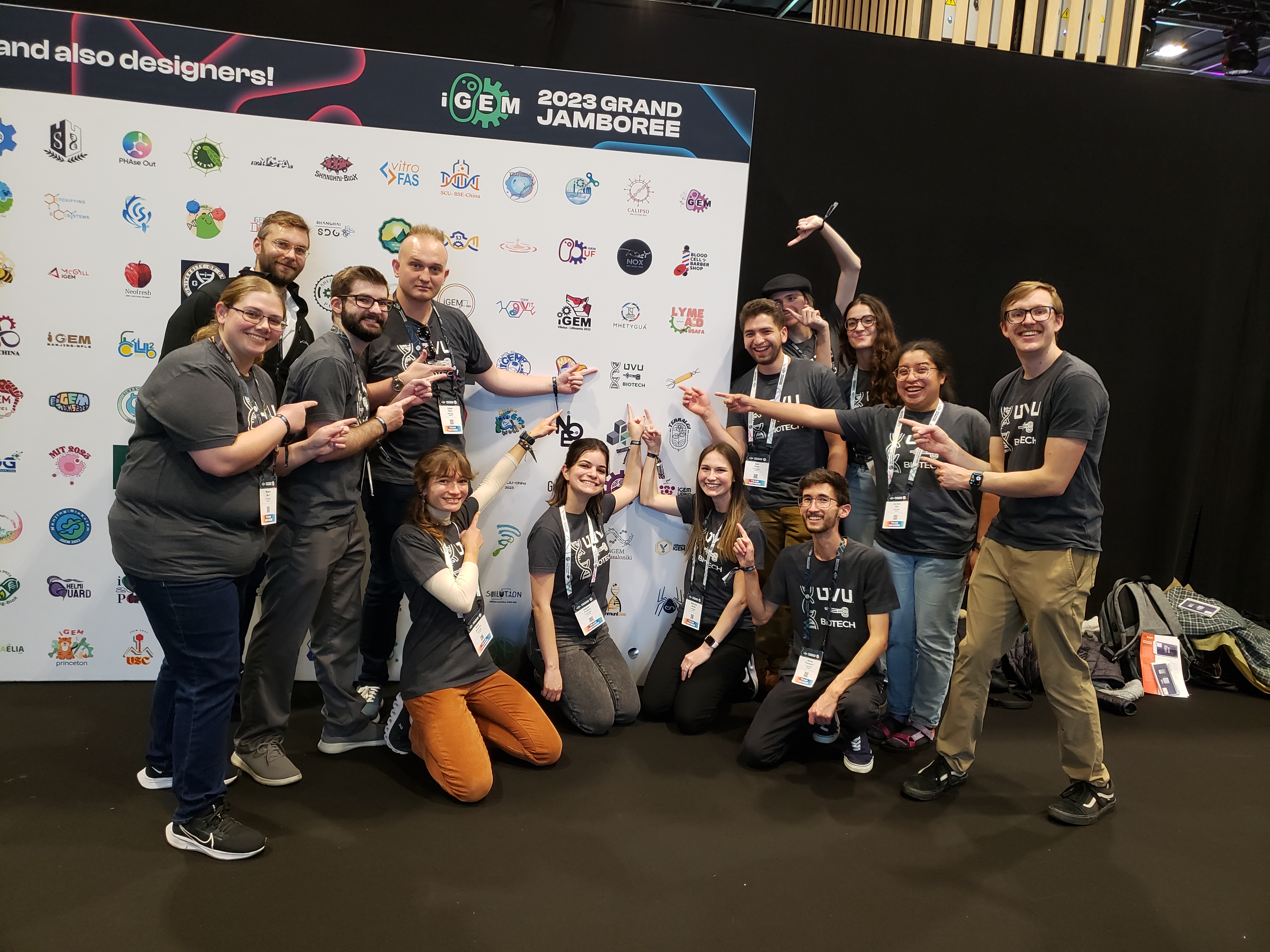 A team of UVU students point to their university's logo on a poster at the International Genetically Engineered Machine Jamboree competition in Paris. The team won a silver medal for its genetically modified algae that could act as a sponge to soak up toxins and prevent harmful algal blooms in the Utah Lake.