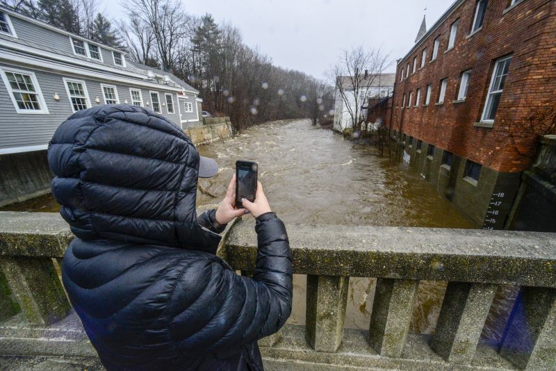 Cassidy Doolittle of Wilmington, Vt., takes a photo of the water marker on the side of a building in downtown Wilmington as the Deerfield River gets to 14 feet high on Monday after a heavy storm dropped a couple of inches of rain.