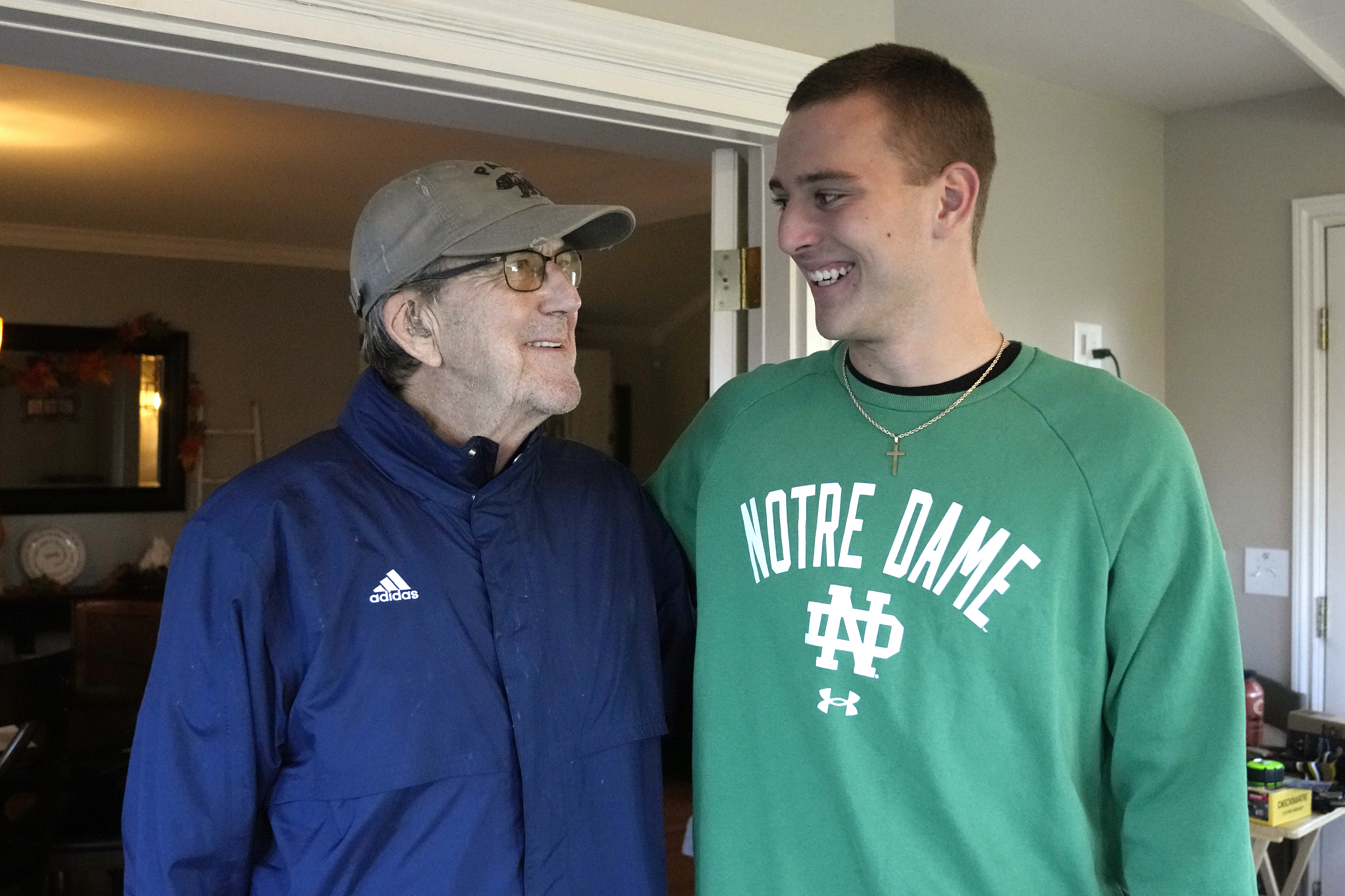 Saline High School quarterback CJ Carr, right, stands next to his grandfather Lloyd Carr, left, Nov. 14, 2023 in Saline, Mich. Carr will be among the hundreds of football players to sign a national letter of intent this week, sealing his commitment to join Notre Dame, but no one has a story quite the same.