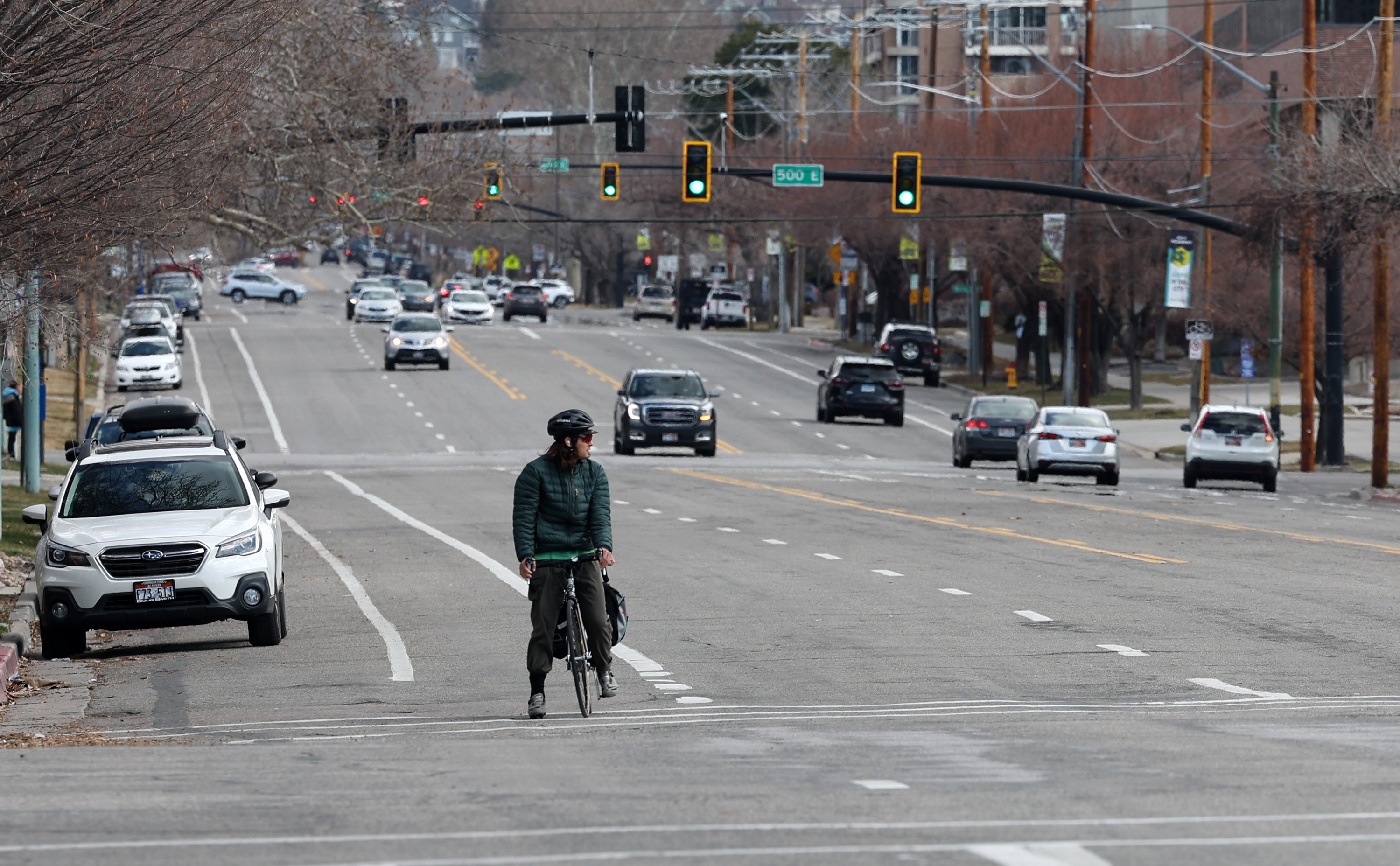 A cyclist watches traffic before crossing 400 East at 200 South in Salt Lake City on Tuesday, March 22, 2022. A $953,600 grant has been awarded to Salt Lake City to help make its streets safer — particularly for K-12 students.