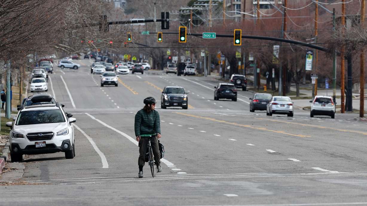 A cyclist watches traffic before crossing 400 East at 200 South in Salt Lake City on Tuesday, March 22, 2022. A $953,600 grant has been awarded to Salt Lake City to help make its streets safer — particularly for K-12 students.