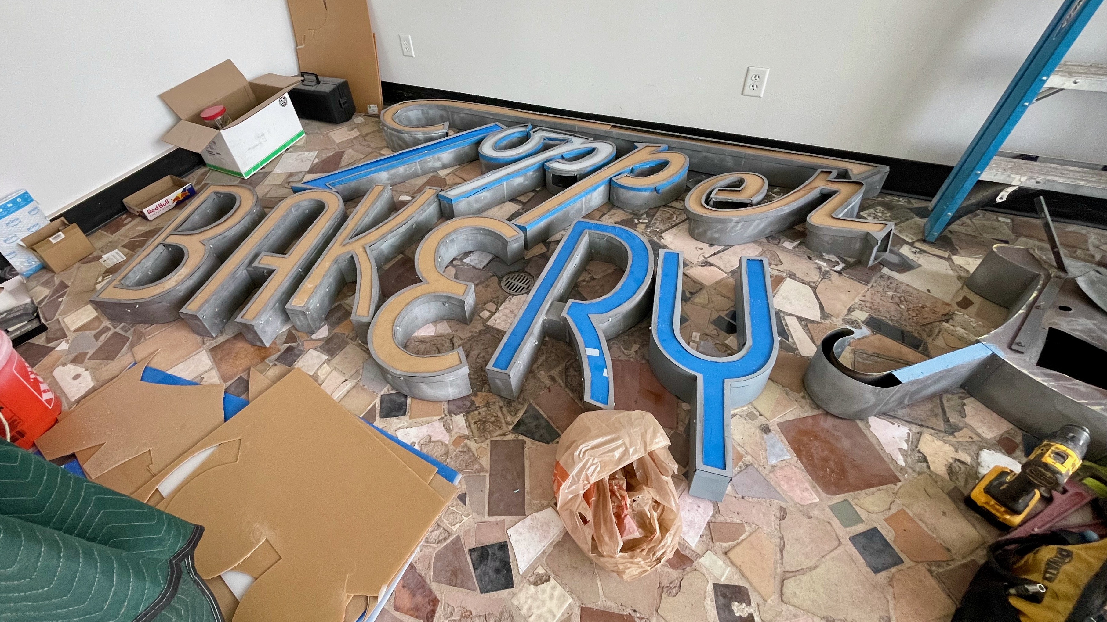 The distinctive Topper Bakery signage sits inside the Ogden locale Monday, waiting to be refurbished. The business was torched in a 2021 fire and the owners hope to reopen next month as rebuilding nears completion.