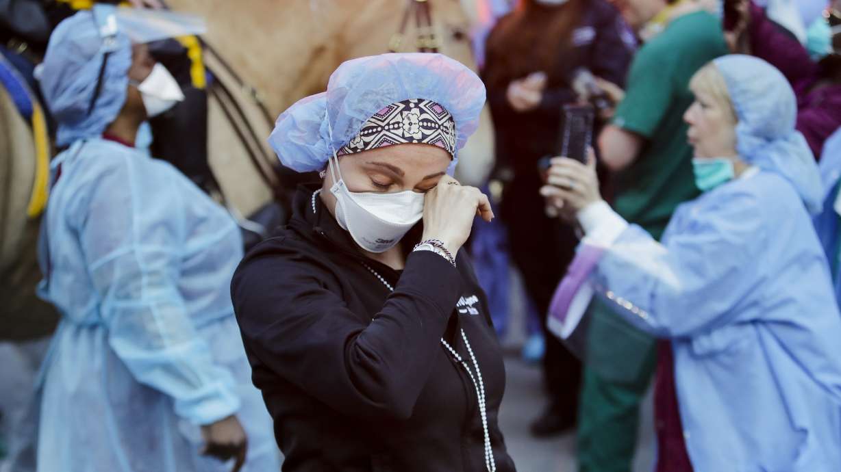 A medical worker reacts as people cheer for them outside NYU Medical Center in New York, April 16, 2020. States that stockpiled millions of masks and other personal protective equipment during the pandemic are throwing the items out.