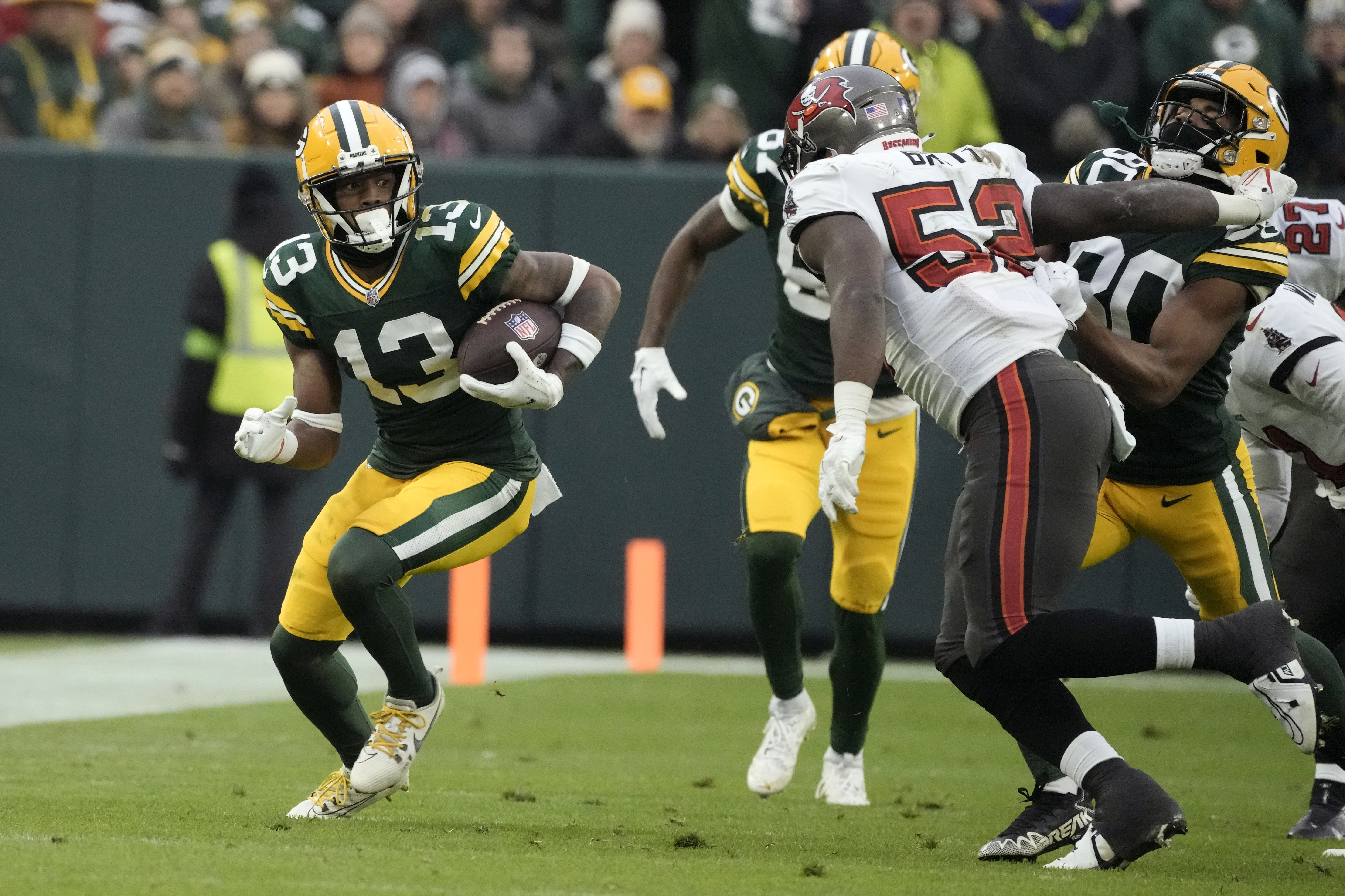 Green Bay Packers wide receiver Dontayvion Wicks (13) catches a pass for a first down during the second half of an NFL football game against the Tampa Bay Buccaneers, Sunday, Dec. 17, 2023, in Green Bay, Wis.