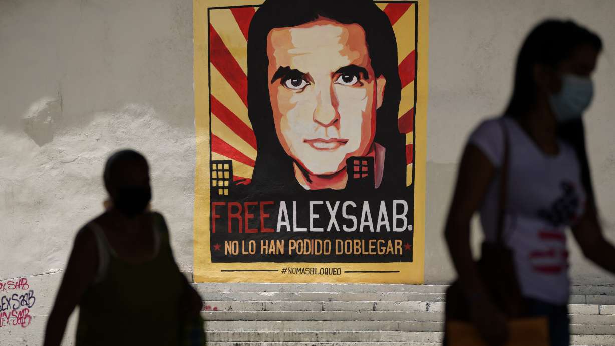 Pedestrians walk near a poster asking for the freedom of Colombian businessman and Venezuelan special envoy Alex Saab, in Caracas, Venezuela, Sept. 9, 2021. The Associated Press has learned that the Biden administration has released a close ally of Venezuelan President Nicolás Maduro in swap for jailed Americans.