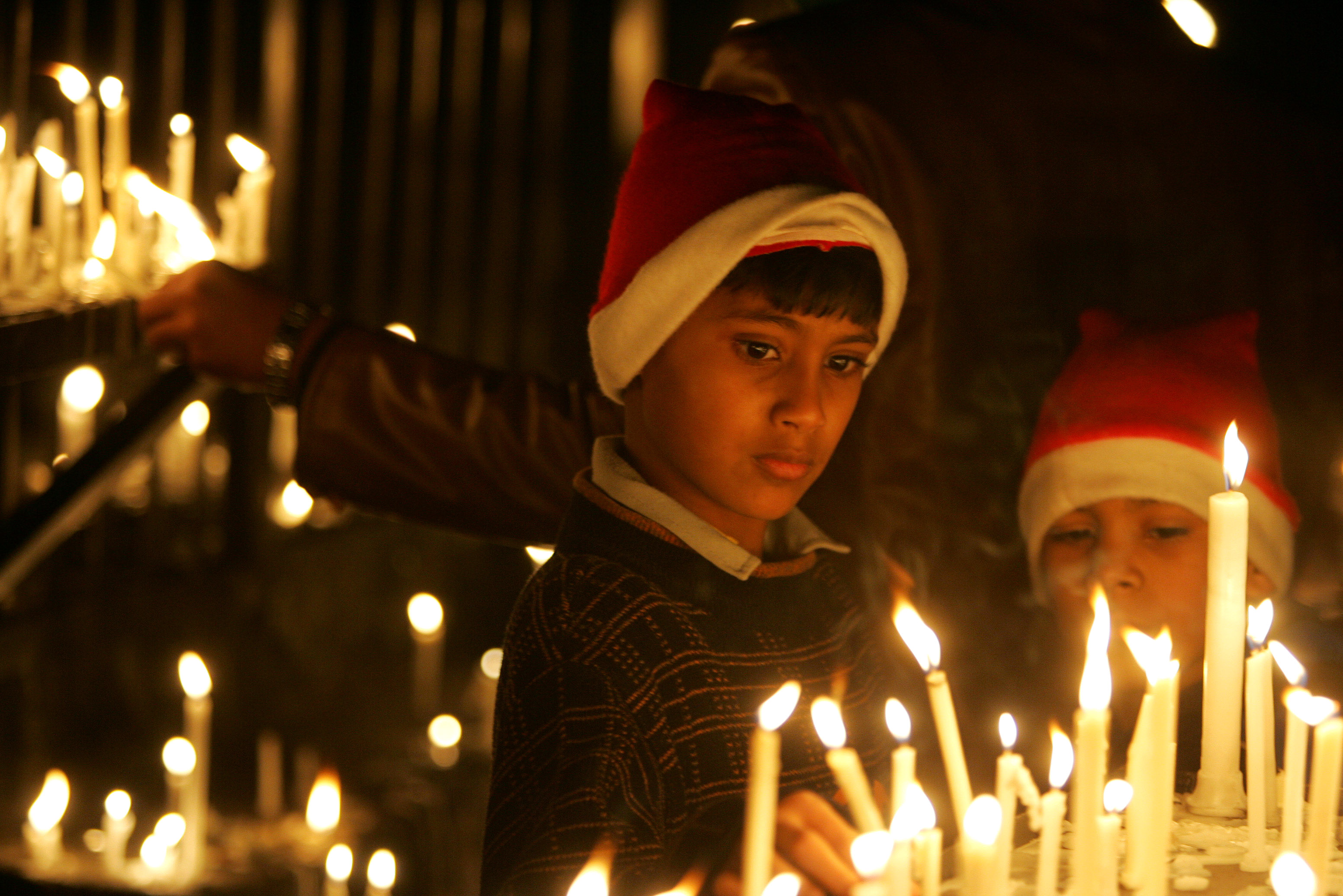 Children light candles at the Sacred Heart Church on Christmas Eve, in New Delhi, India, Saturday, Dec. 24, 2005.