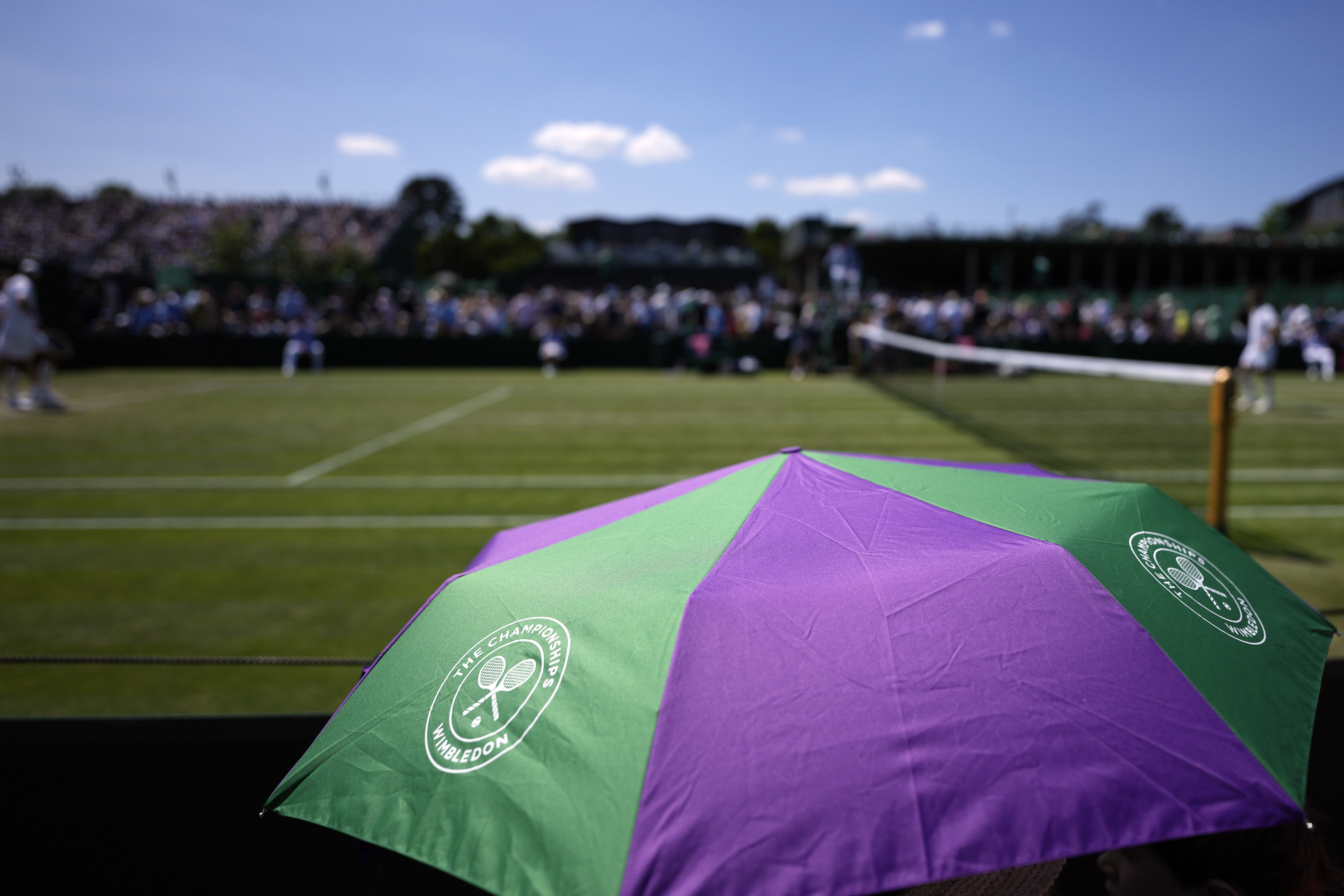 FILE - Spectators shade from the sun under an umbrella on Court 10 on day five of the Wimbledon tennis championships in London, Friday, July 7, 2023. A new monitoring service will help protect tennis players from online abuse and threats. In their joint announcement the International Tennis Federation, U.S. Tennis Association, the All England Club and the women's WTA tour say the “Threat Matrix” service will operate in 35 languages when it launches Jan. 1.