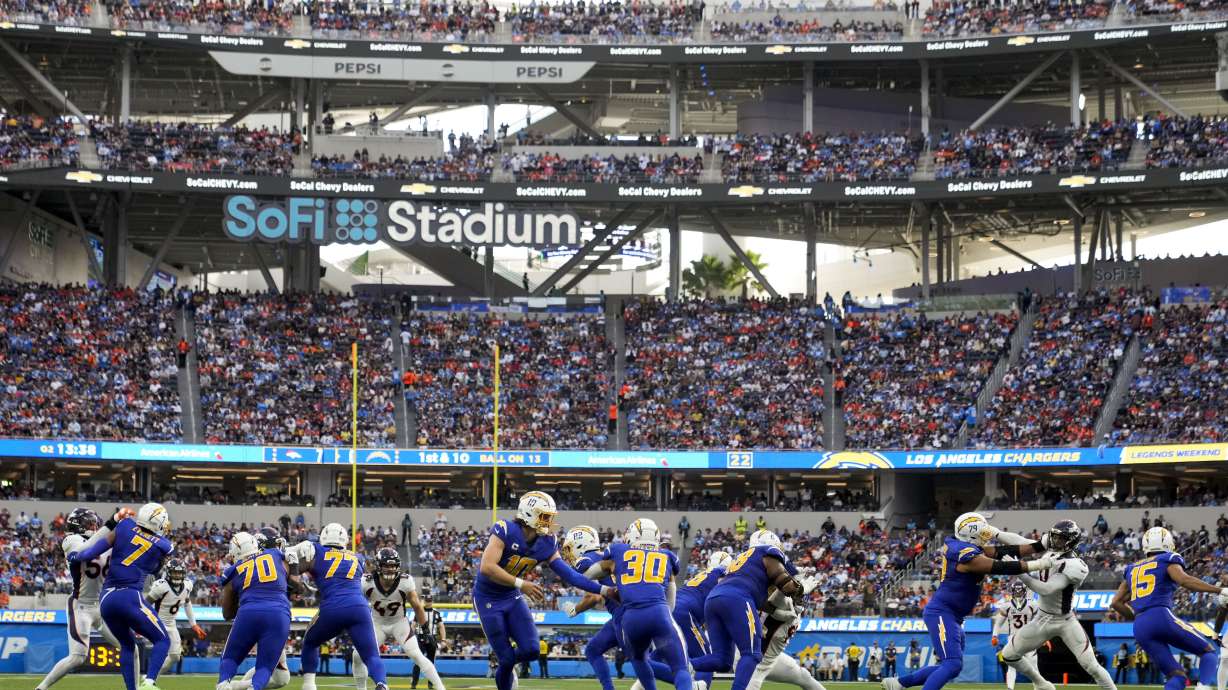 Los Angeles Chargers quarterback Justin Herbert (10) hands the ball to running back Austin Ekeler (30) during the first half of an NFL football game against the Denver Broncos Sunday, Dec. 10, 2023, in Inglewood, Calif.
