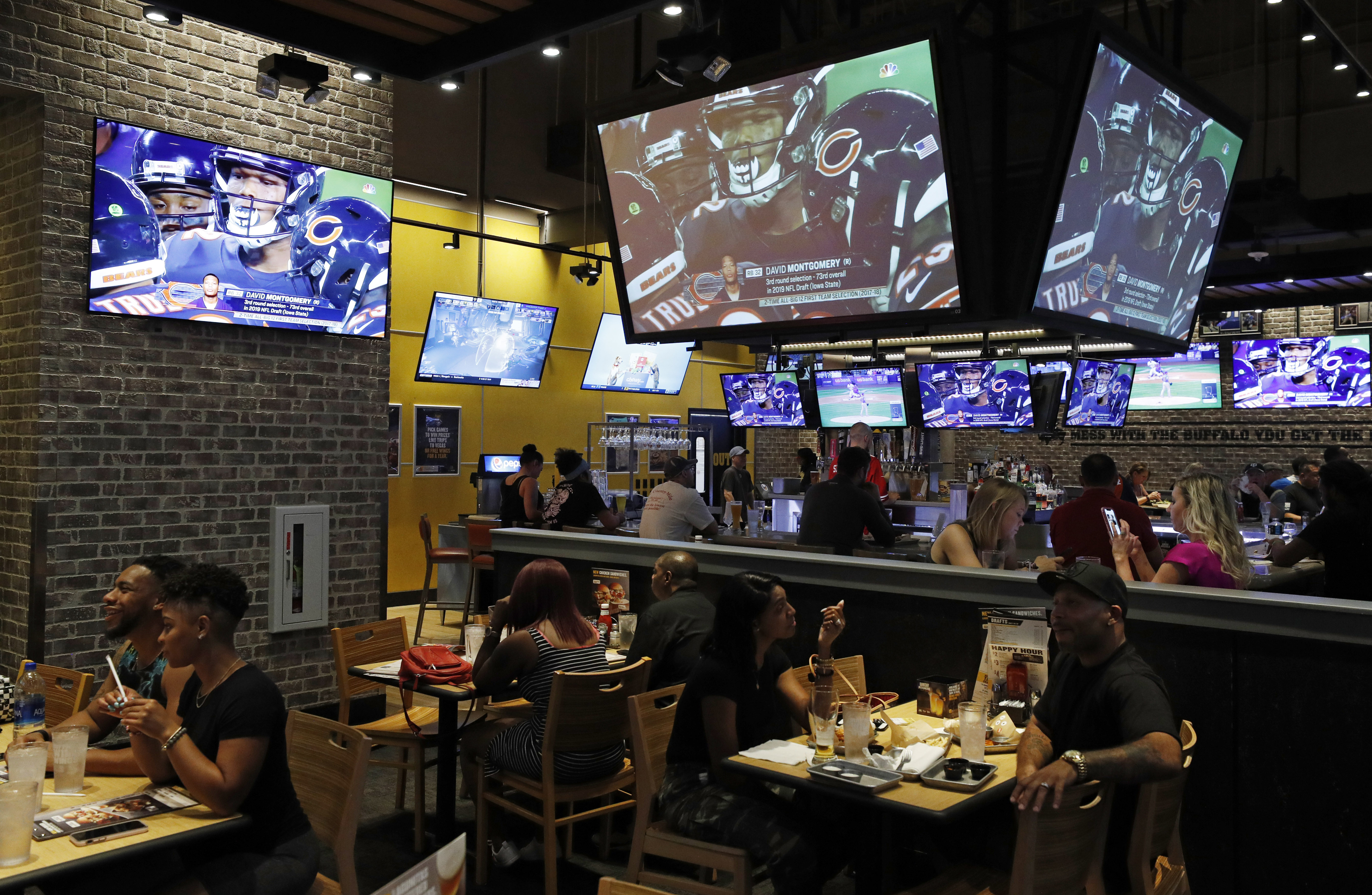 People eat and watch football at a Buffalo Wild Wings, Sept. 5, 2019, in Las Vegas. There is no denying the pleasure and madness of fantasy football, and it seems like everyone is taking part these days.