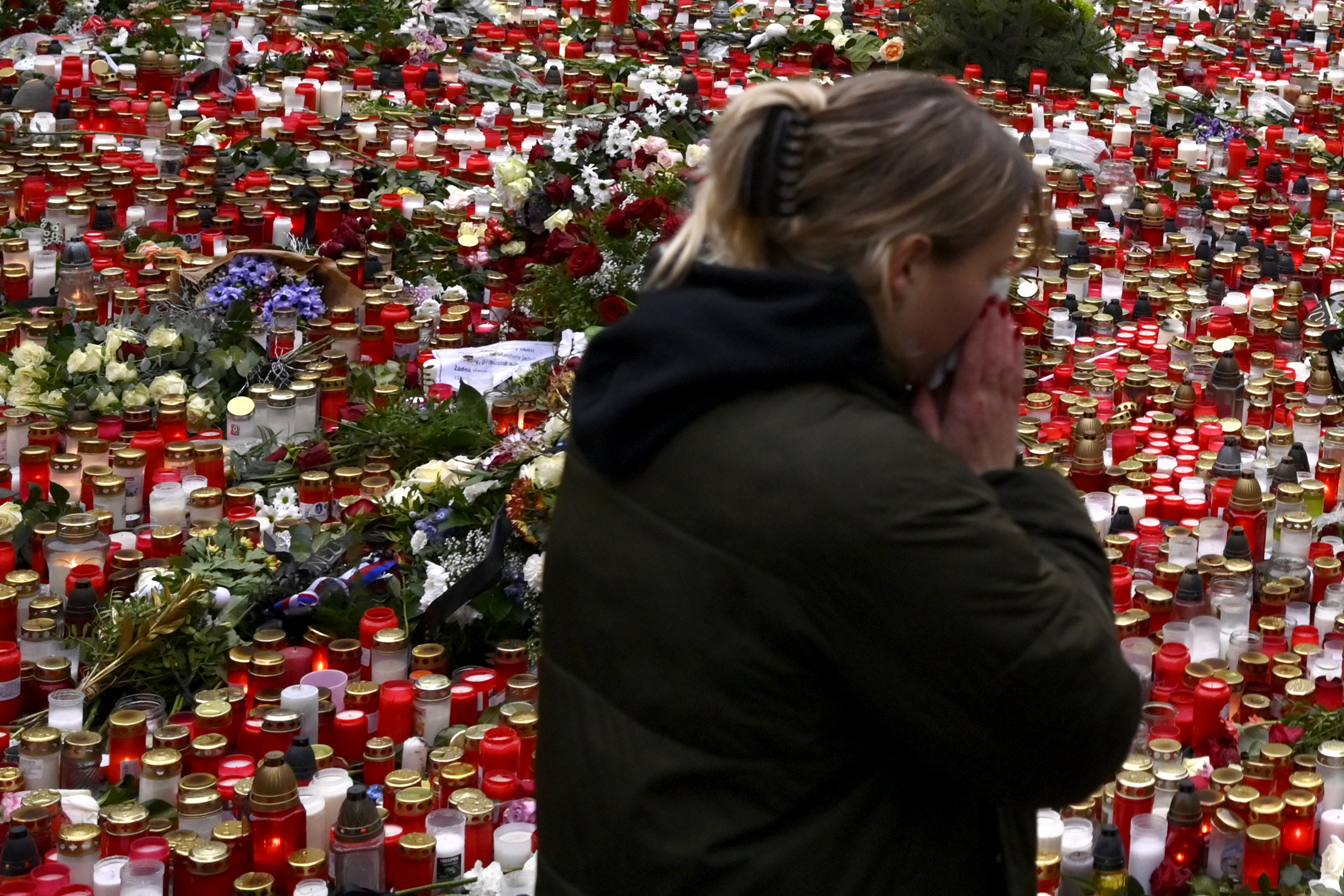 A young woman reacts to the floral tributes and candles left outside the headquarters of Charles University in downtown Prague, Czech Republic, Saturday. A lone gunman opened fire at a university on Thursday.