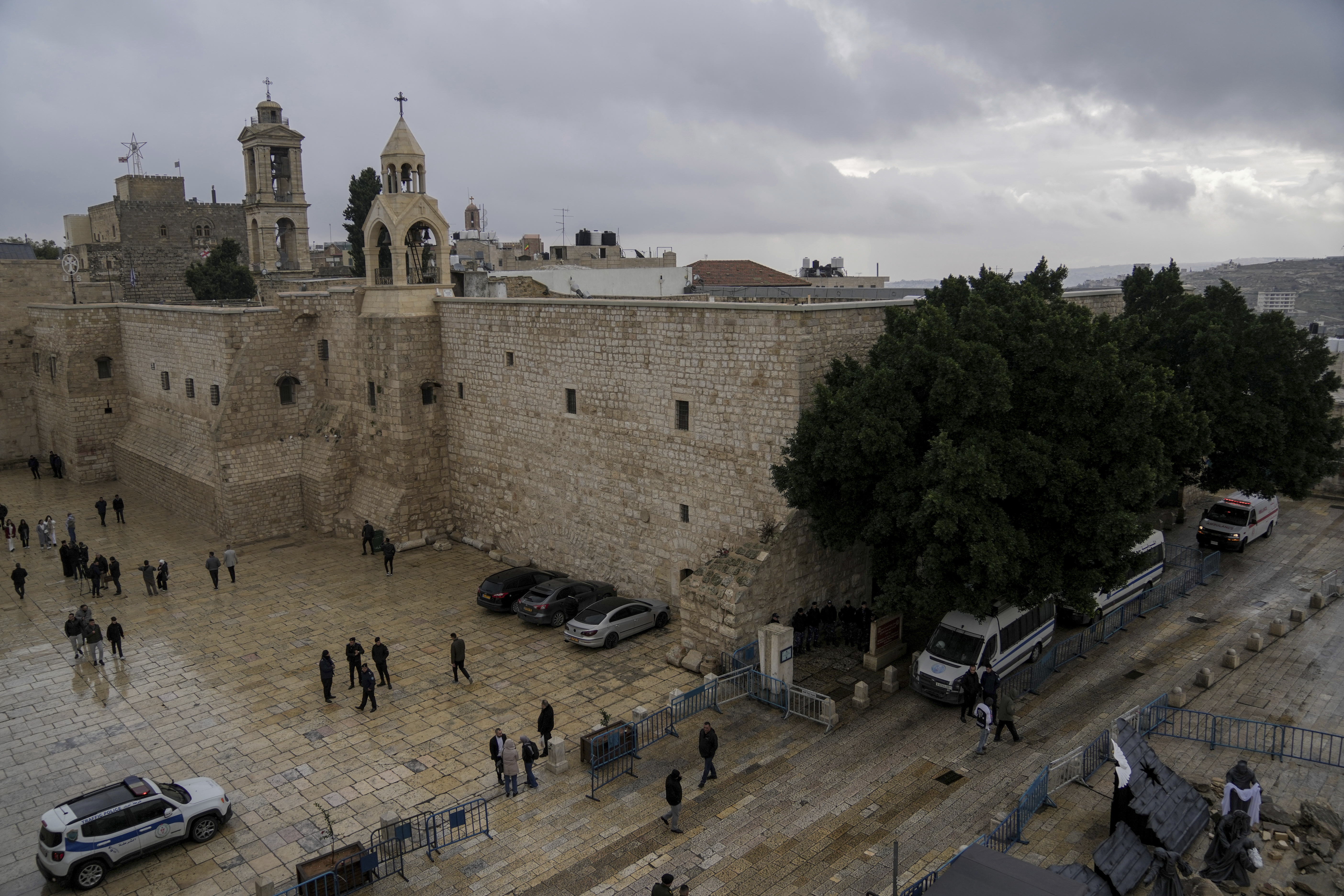 People walk by the Church of the Nativity, traditionally believed to be the birthplace of Jesus, on Christmas Eve, in the West Bank city of Bethlehem, Sunday. Bethlehem is having a subdued Christmas after officials decided to forgo celebrations.
