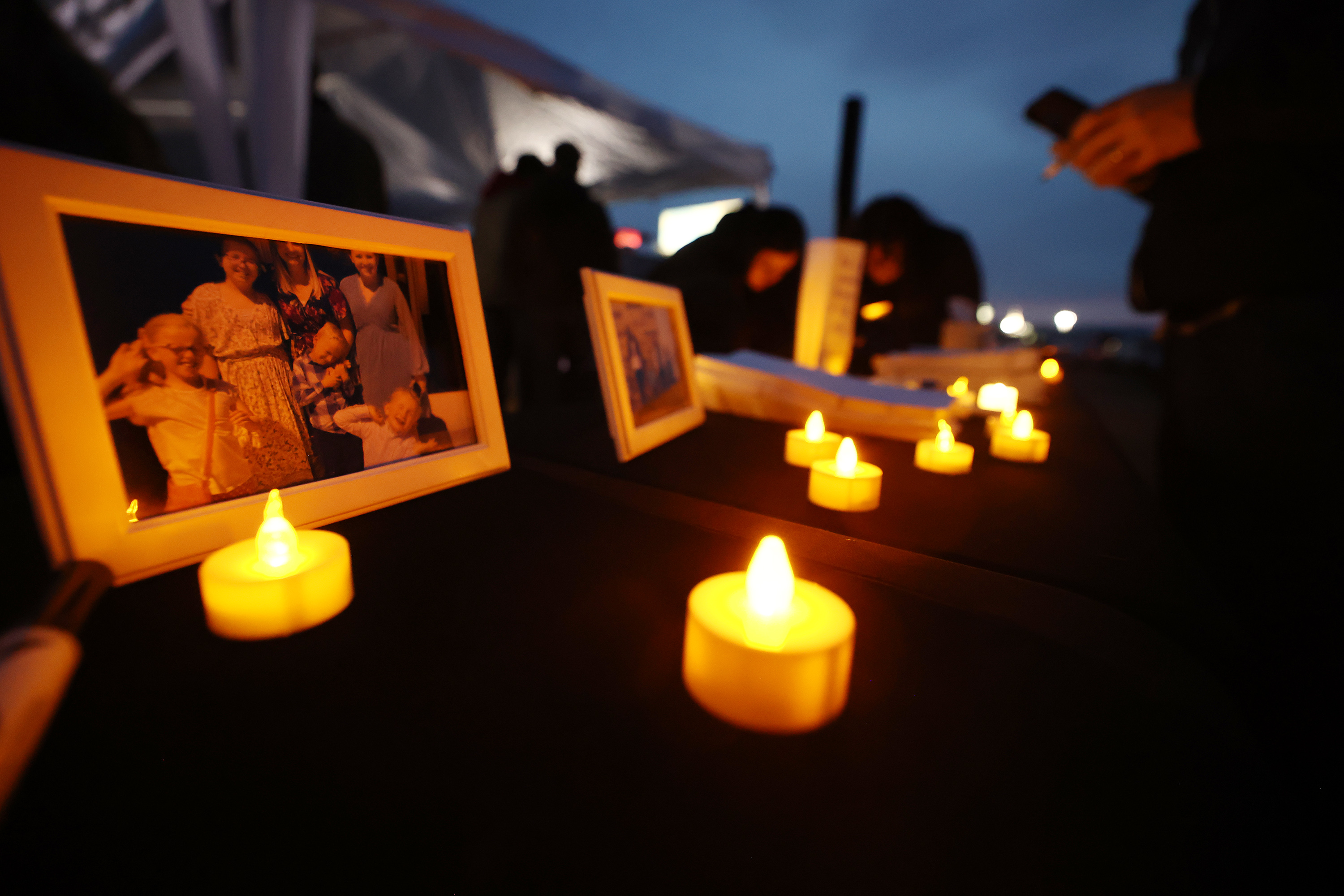 Photos are on display as residents of the town of Enoch, in Iron County, come together in honor of Gail Earl and the Haight Family at a vigil at the sports complex in Enoch on Jan. 13.