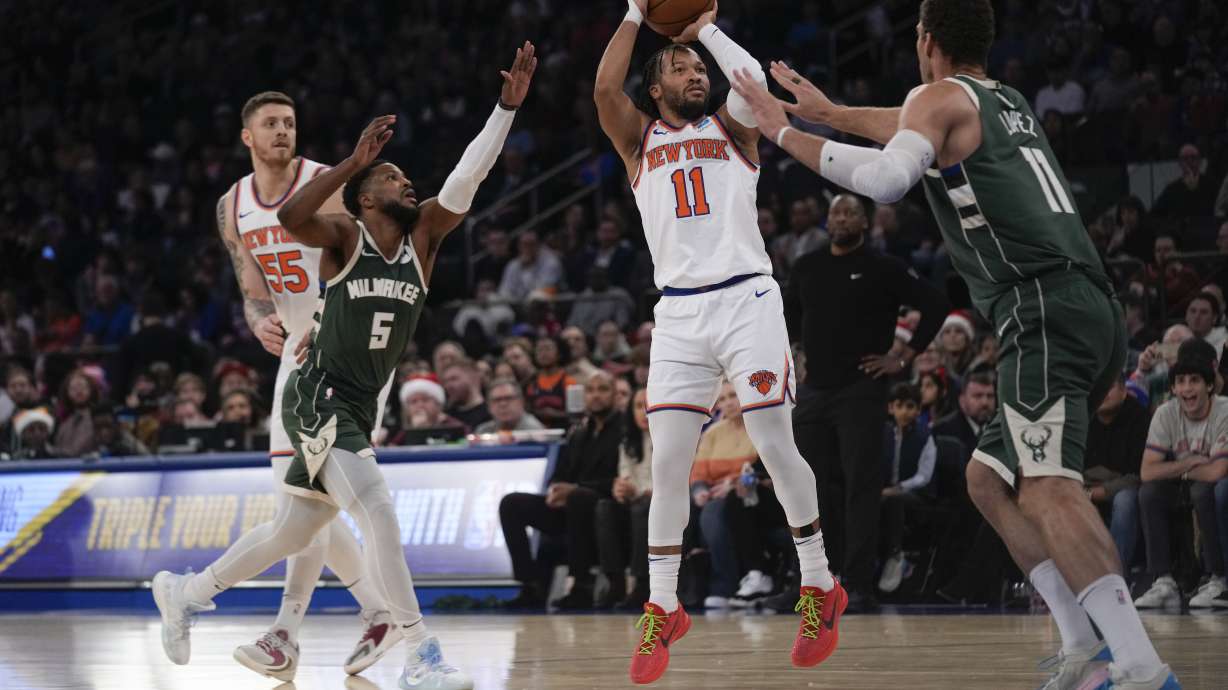New York Knicks' Jalen Brunson (11), second from right, puts up a shot over Milwaukee Bucks' Brook Lopez, right, during the first half of an NBA basketball game, Monday, Dec. 25, 2023, in New York.