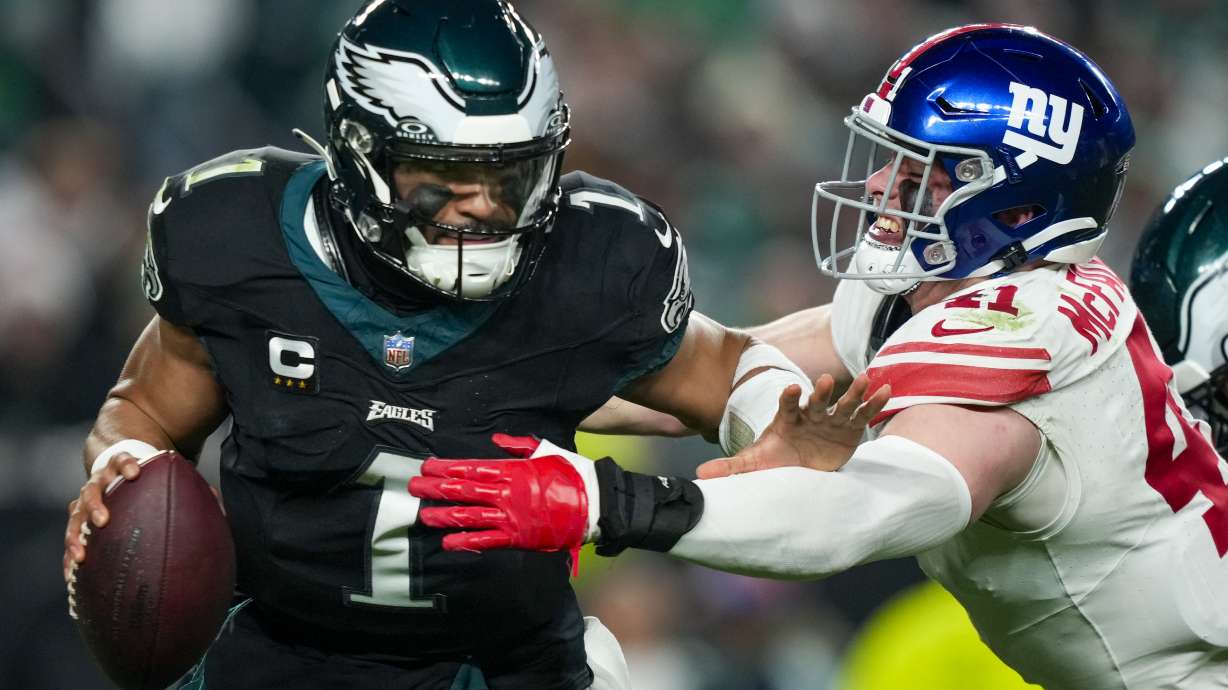 Philadelphia Eagles quarterback Jalen Hurts pushes off New York Giants linebacker Micah McFadden during the first half of an NFL football game Monday, Dec. 25, 2023, in Philadelphia.