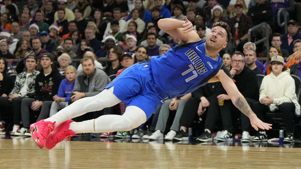 Dallas Mavericks guard Luka Doncic reacts after getting knocked to the ground during the first half of an NBA basketball game against the Phoenix Suns, Monday, Dec. 25, 2023, in Phoenix.