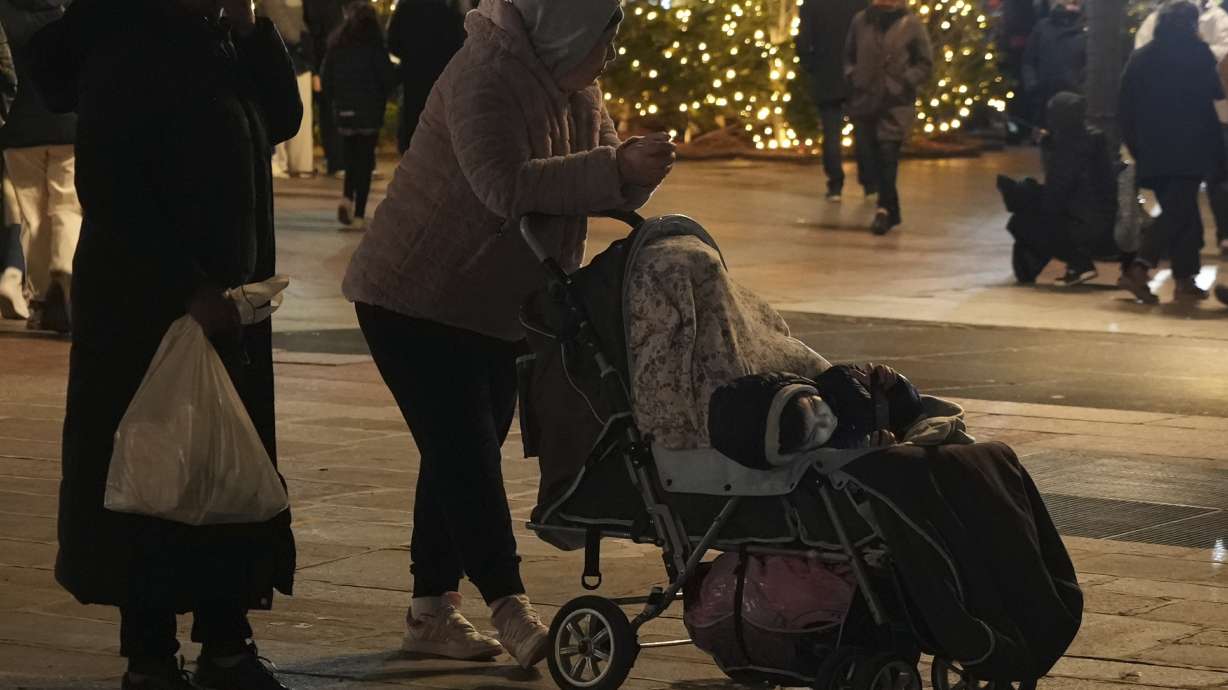 Migrants wait on the City Hall plaza in Paris, Monday Dec.25, 2023 as migrant families meet on Christmas Day seeking somewhere to stay. About 50 families with children between three months and 10 years old gathered on City Hall plaza on Christmas evening, to meet members of aid groups who distribute food, blankets and diapers and help find temporary lodging.