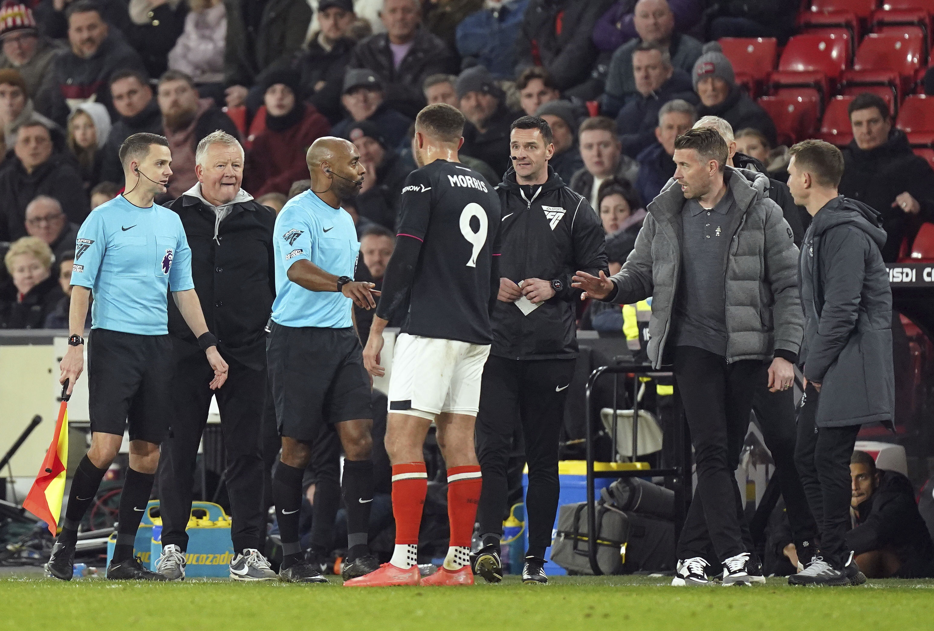 Luton Town's Carlton Morris, centre, speaks to referee Sam Allison on the touchline as managers Rob Edwards and Chris Wilder look on during the English Premier League soccer match between Sheffield United and Luton Town at Bramall Lane, in Sheffield, England, Tuesday, Dec. 26, 2023. Luton manager Rob Edwards says player Carlton Morris spoke to the police after an alleged racist comment was made toward him during his team’s Premier League match against Sheffield United.