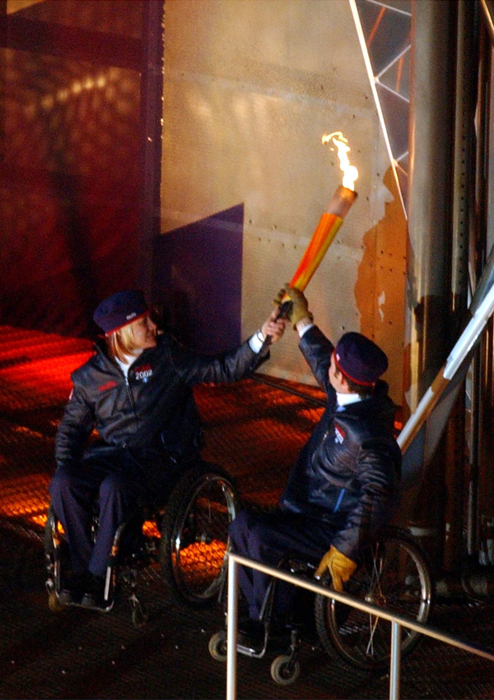 Paralympians Muffy Davis, left, and Chris Waddell, right, light the cauldron during the 2002 Paralympic Opening Ceremony in Salt Lake City, March 7, 2002.