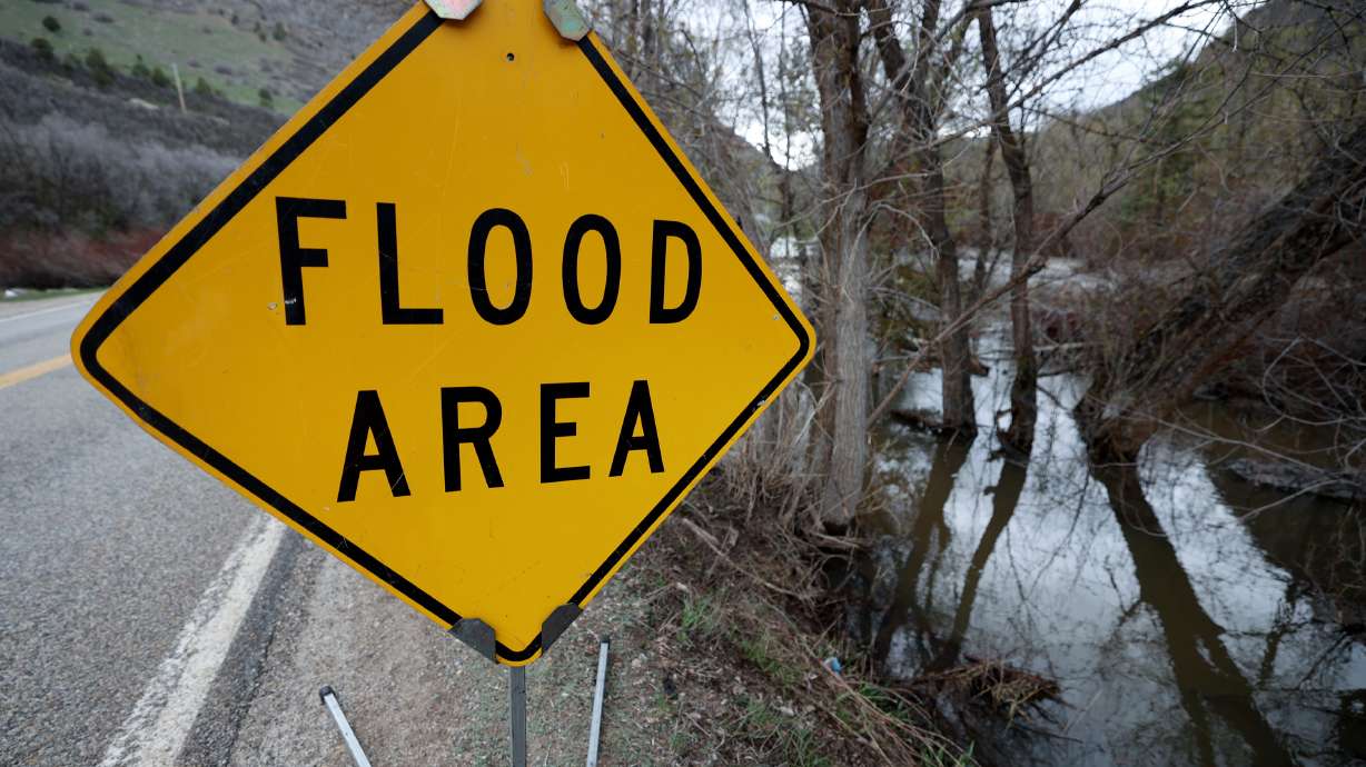 A road sign warns of flooding next to the South Fork Ogden River after a record snowfall year in Weber County on May 8. The Biden administration announced federal disaster funds will be available to five Utah counties for flood damage.