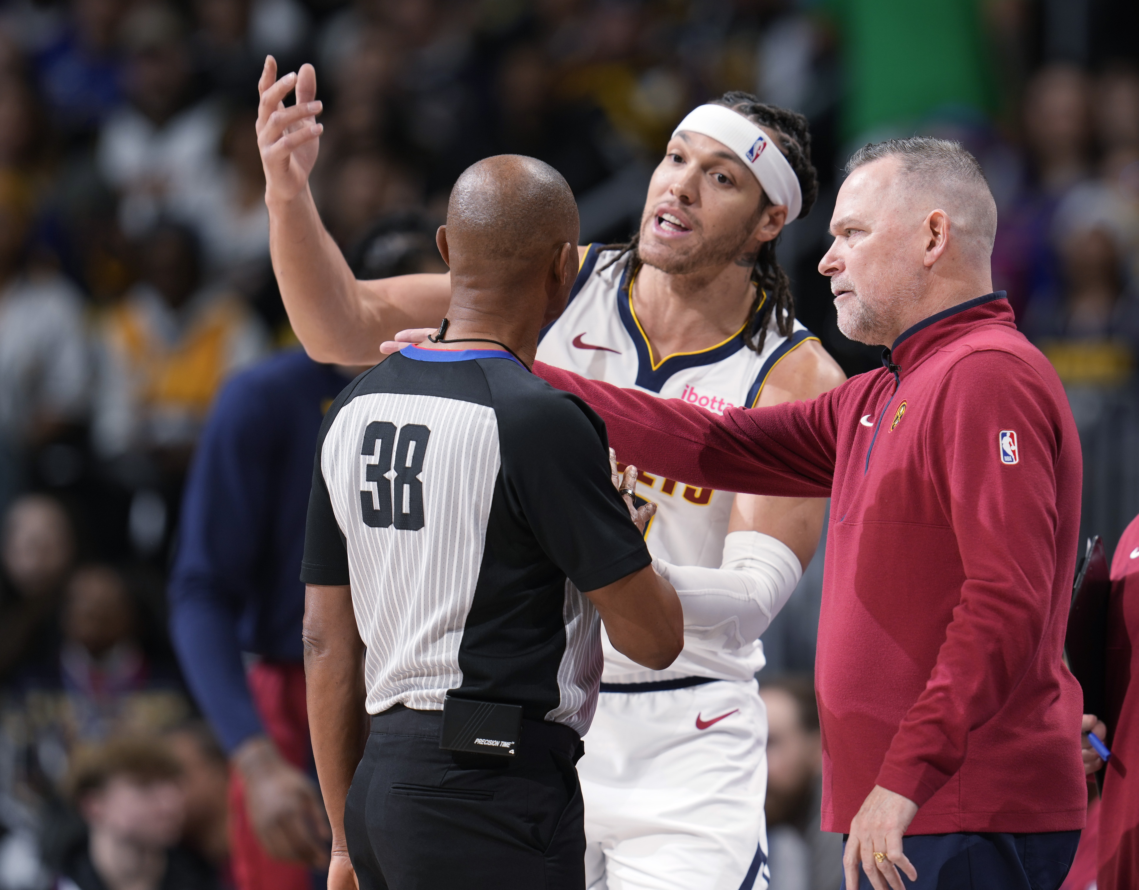 Denver Nuggets forward Aaron Gordon, center, argues after being called for a foul with referee Michael Smith, left, as head coach Michael Malone looks on in the first half of an NBA basketball game against the Golden State Warriors Monday, Dec. 25, 2023, in Denver. 