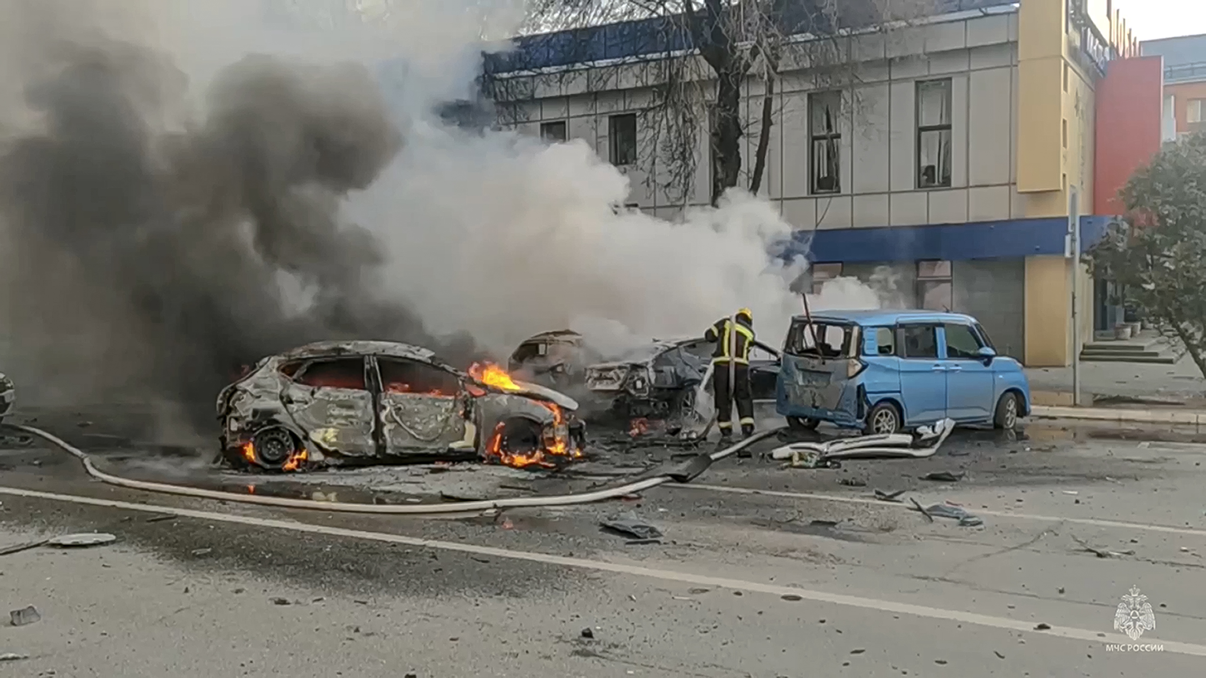 In this photo taken from video released by Russia Emergency Situations Ministry telegram channel on Saturday, firefighters extinguish burning cars after shelling in Belgorod, Russia.