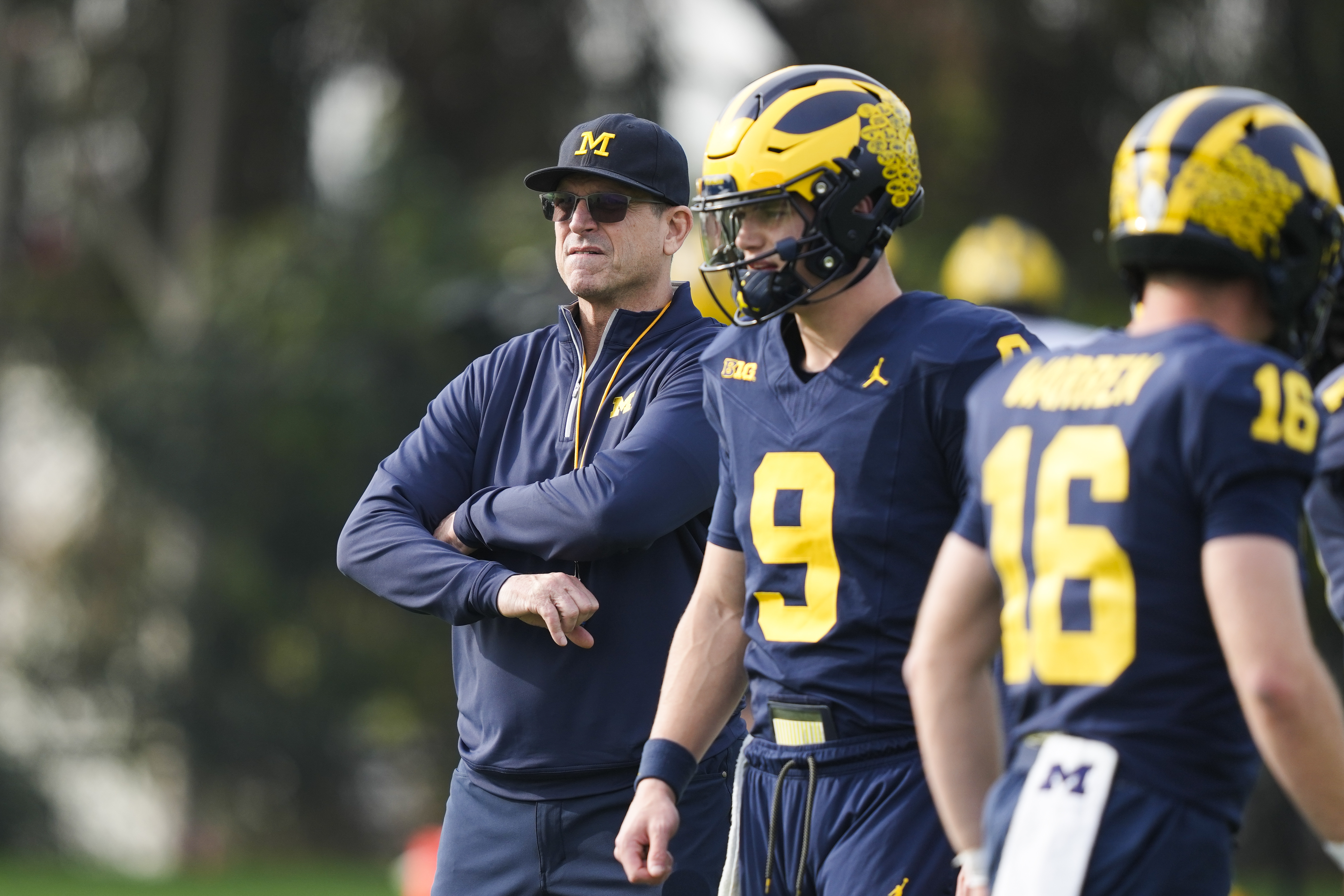 Michigan head coach Jim Harbaugh, left, stands near quarterbacks J.J. McCarthy (9) and Davis Warren (16) during NCAA college football practice Friday, Dec. 29, 2023, in Carson, Calif. Michigan is scheduled to play against Alabama on New Year's Day in the Rose Bowl, a semifinal in the College Football Playoff.