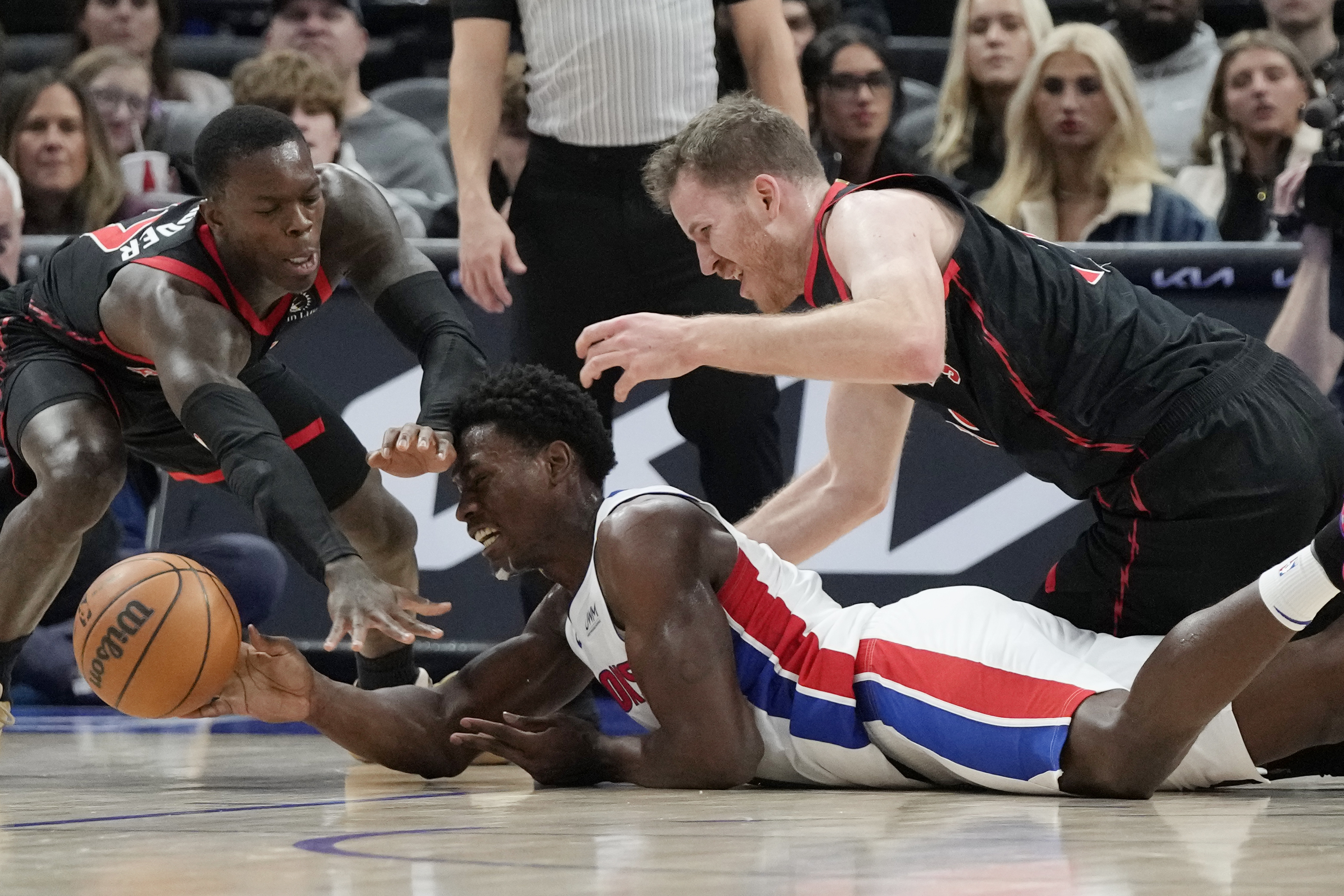 Toronto Raptors guard Dennis Schroder, left, and center Jakob Poeltl (19) reach in on Detroit Pistons center Jalen Duren during the first half of an NBA basketball game, Saturday, Dec. 30, 2023 in Detroit.