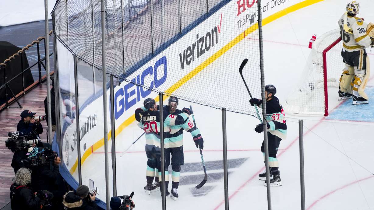 Seattle Kraken right wing Eeli Tolvanen (20) celebrates his goal with teammates right wing Oliver Bjorkstrand (22) and center Yanni Gourde (37) as Vegas Golden Knights goaltender Logan Thompson (36) looks away during the first period of the NHL Winter Classic hockey game Monday, Jan. 1, 2024, in Seattle.