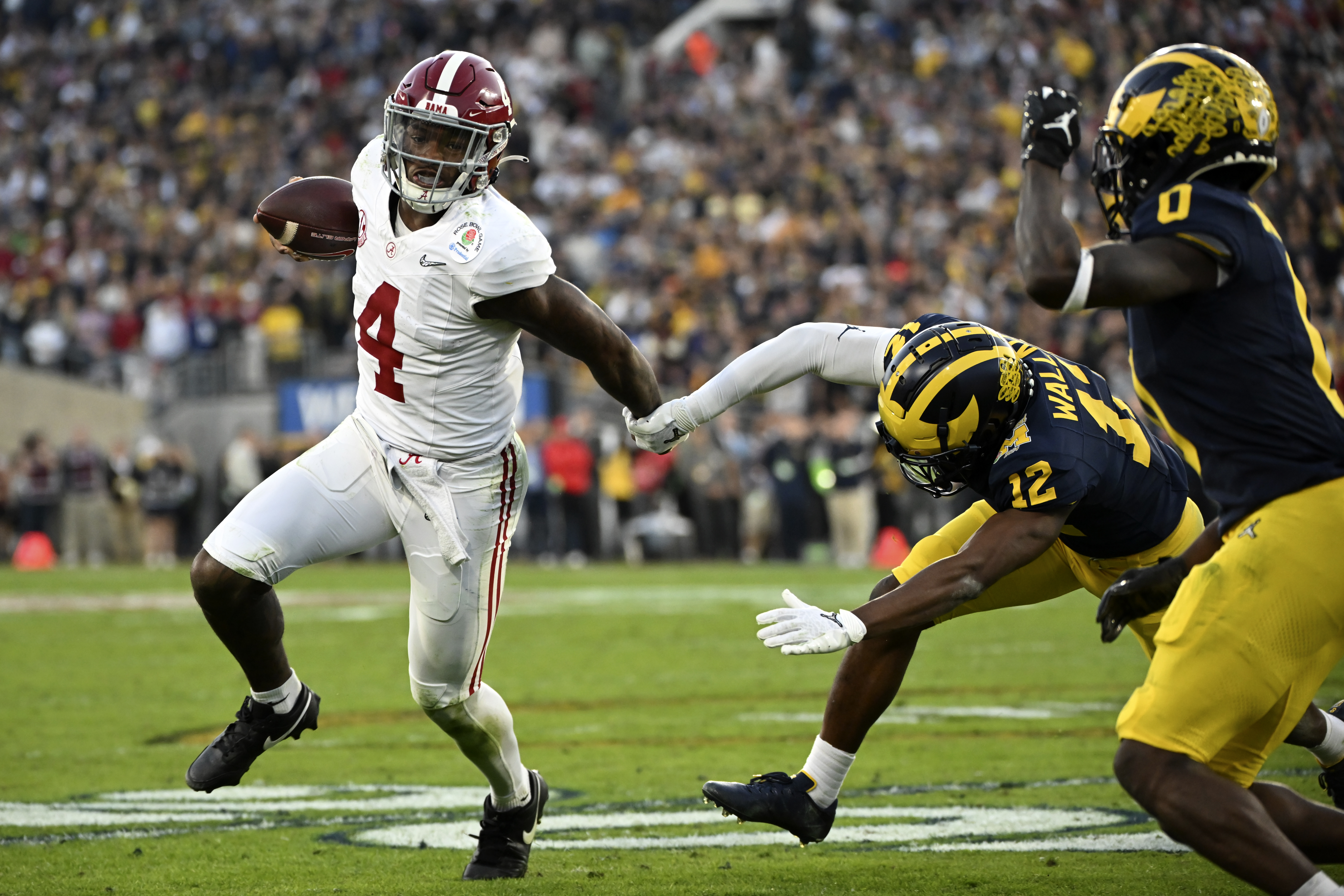 Alabama quarterback Jalen Milroe (4) is chased by Michigan defensive back Josh Wallace (12) during the second half of the Rose Bowl CFP NCAA semifinal college football game Monday, Jan. 1, 2024, in Pasadena, Calif. 