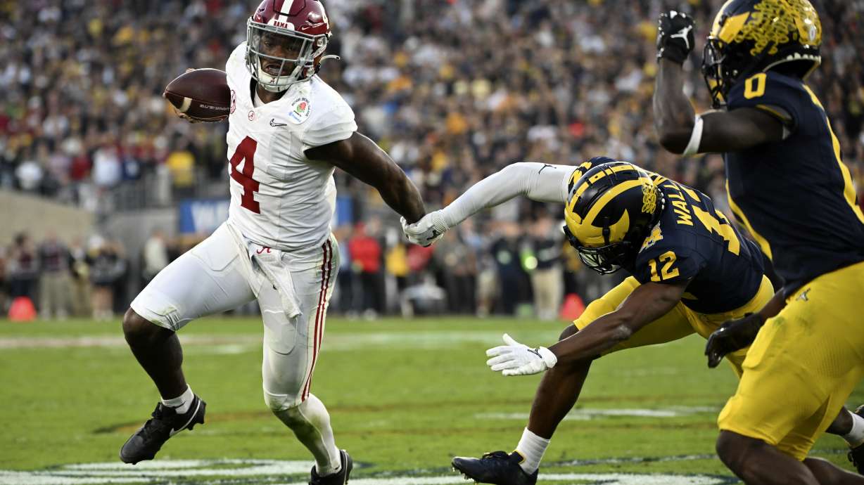 Alabama quarterback Jalen Milroe (4) is chased by Michigan defensive back Josh Wallace (12) during the second half of the Rose Bowl CFP NCAA semifinal college football game Monday, Jan. 1, 2024, in Pasadena, Calif.