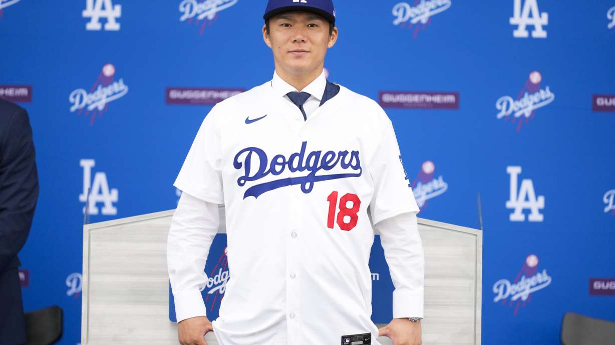 Yoshinobu Yamamoto poses wearing his No. 18 Dodgers baseball jersey during a media presentation, in Los Angeles, Dec. 27, 2023. The consensus best pitcher outside North America joined the Dodgers on a 12-year contract that's reportedly the largest and longest ever guaranteed to a major league pitcher.