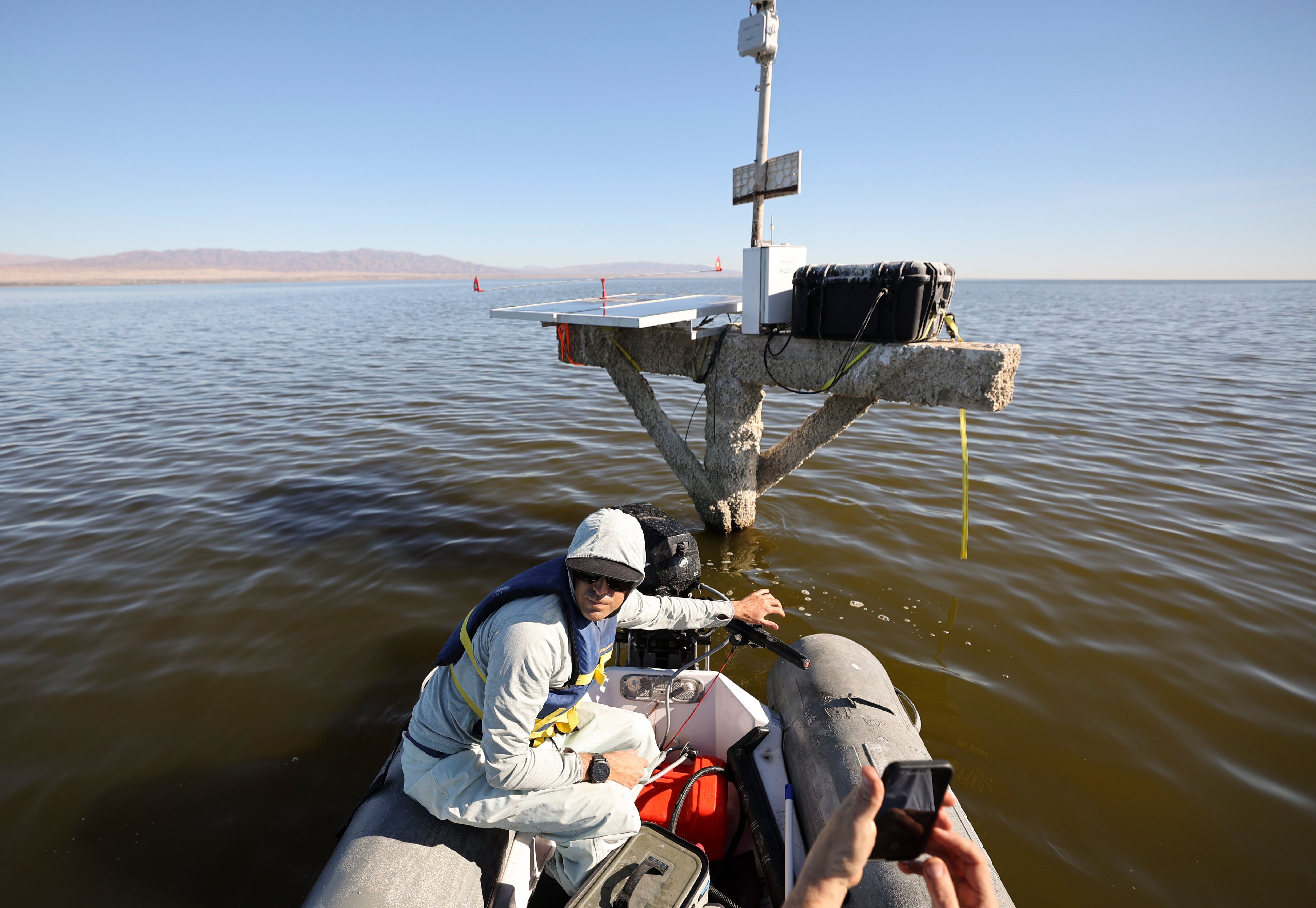 Quinn Montgomery, Alianza consultant biologist, steers a boat away from a solar powered hydrogen sulfide sensor in the Salton Sea, Calif., on Dec. 14, 2023. The sensor also measures nitrogen dioxide and volatile organic compounds. Hydrogen sulfide is a toxic gas that smells of rotten eggs.