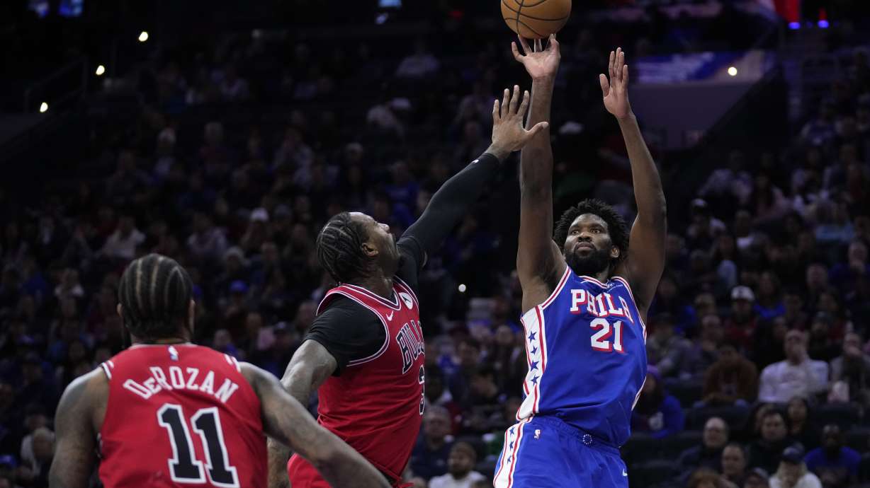 Philadelphia 76ers' Joel Embiid, right, goes up for a shot against Chicago Bulls' Andre Drummond, center, during the first half of an NBA basketball game, Tuesday, Jan. 2, 2024, in Philadelphia.