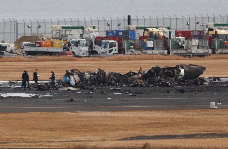 Officials investigate a burnt Japan Coast Guard aircraft after a collision with Japan Airlines' Airbus A350 plane at Haneda International Airport in Tokyo, Japan, Wednesday.