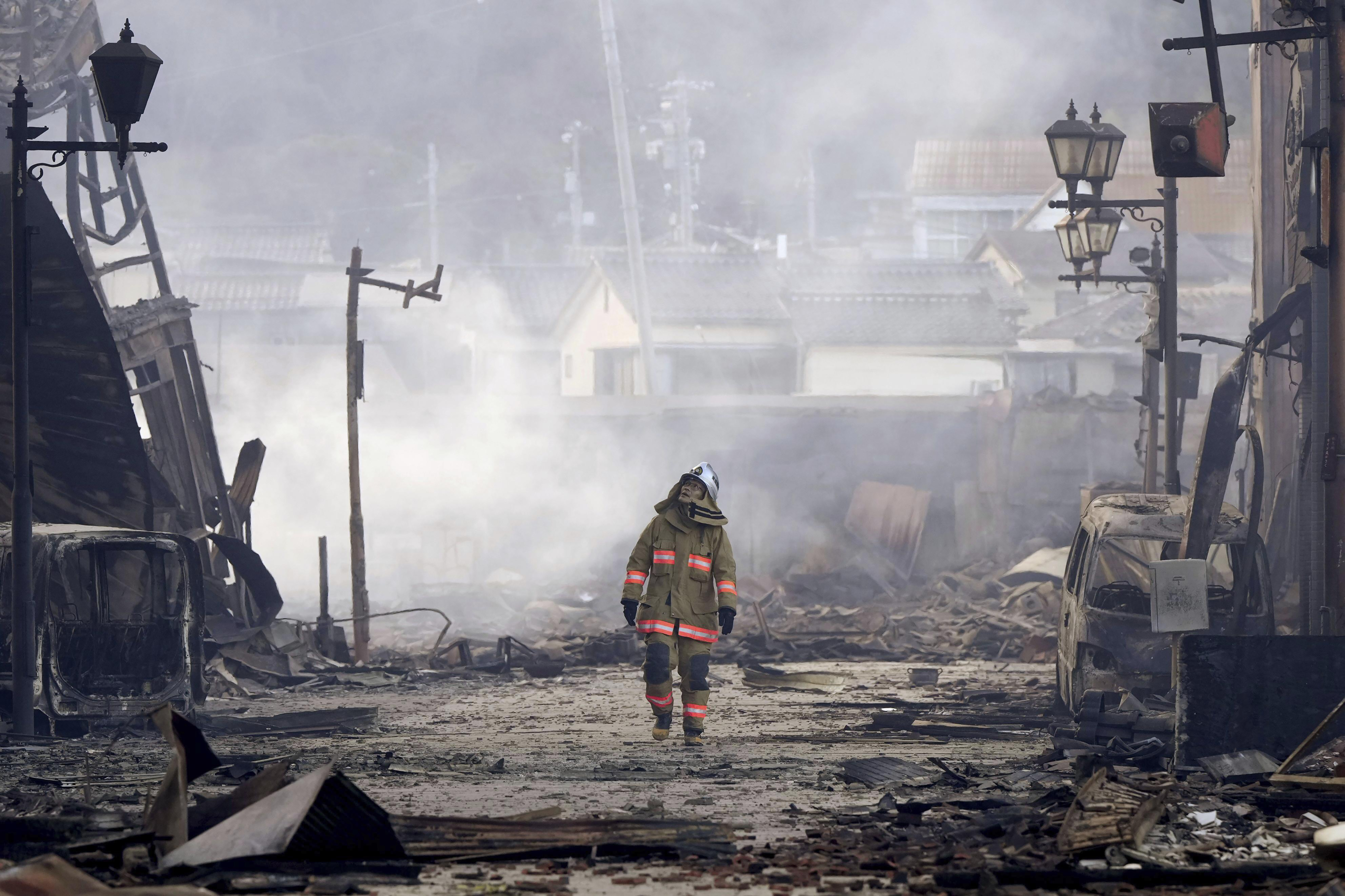 A firefighter walks through the rubble and wreckage of a burnt-out marketplace following earthquake in Wajima, Ishikawa prefecture, Japan, Tuesday. 