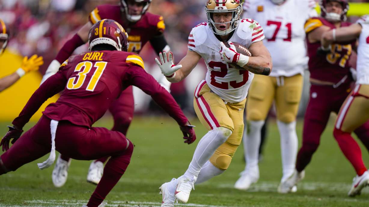 San Francisco 49ers running back Christian McCaffrey (23) runs up against Washington Commanders safety Kamren Curl (31) during the first half of an NFL football game, Sunday, Dec. 31, 2023, in Landover, Md.