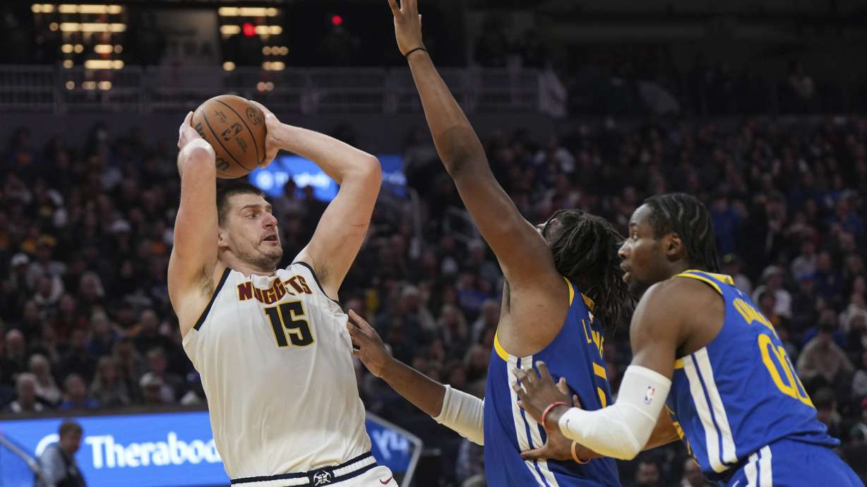 Denver Nuggets center Nikola Jokic (15) looks to pass as Golden State Warriors forward Kevon Looney, center, and forward Jonathan Kuminga, right, defend during the first half of an NBA basketball game Thursday, Jan. 4, 2024, in San Francisco.