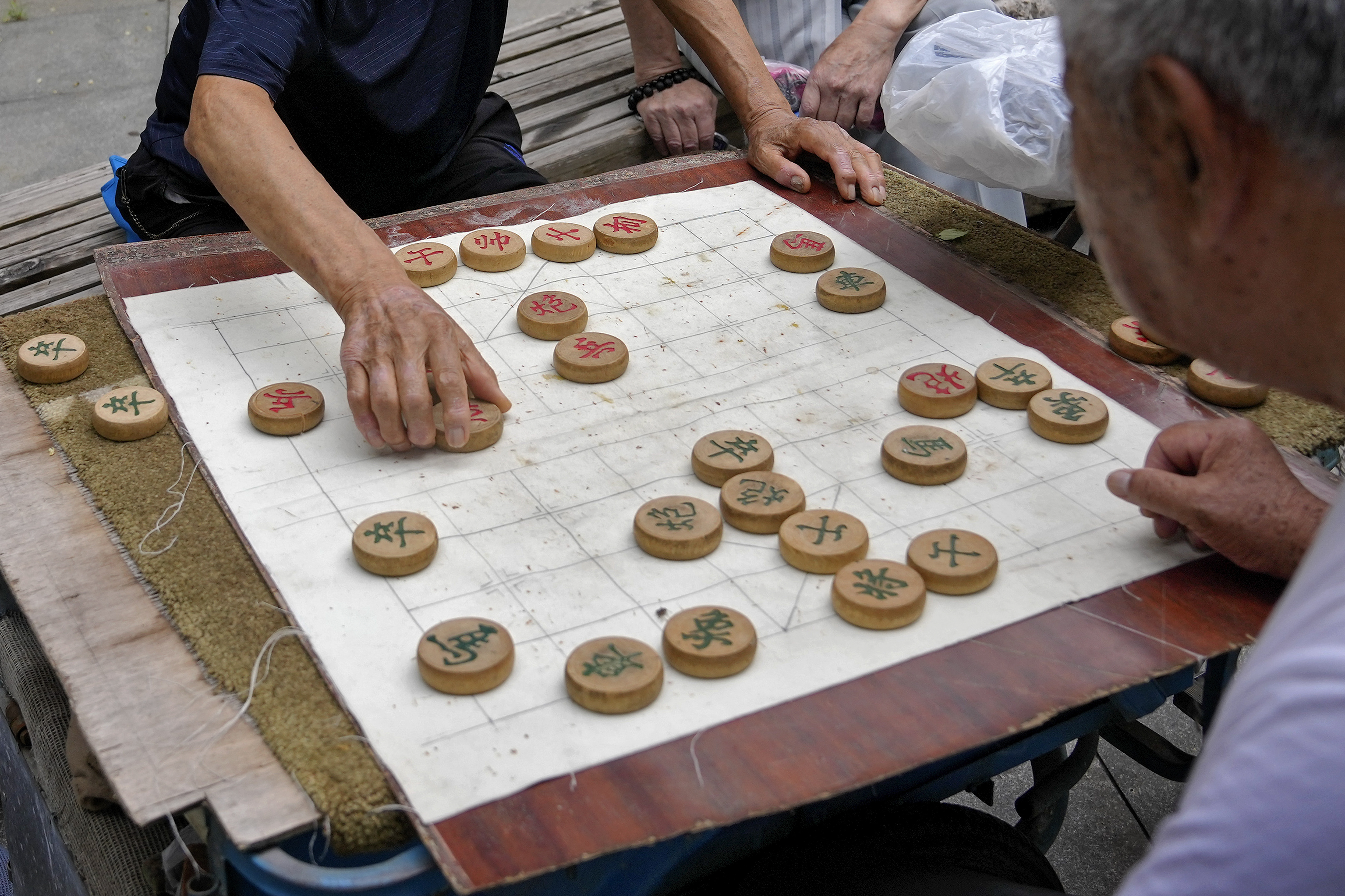 FILE - Residents play Chinese chess games outside a residential area in Beijing on July 19, 2021. A competitor in Chinese chess says he has sued the national association in China for mental distress after he was stripped of a title for drinking alcohol and defecating in the bathtub of his hotel room at a recent competition. Yan Chenglong 's complaint — which demands that the association apologize, restore his reputation in the media and pay him 100,000 yuan ($14,000) in damages — was mailed to a court in central China's Henan province on Monday, Jan. 1, 2024, according to a post on Yan's social media account. 