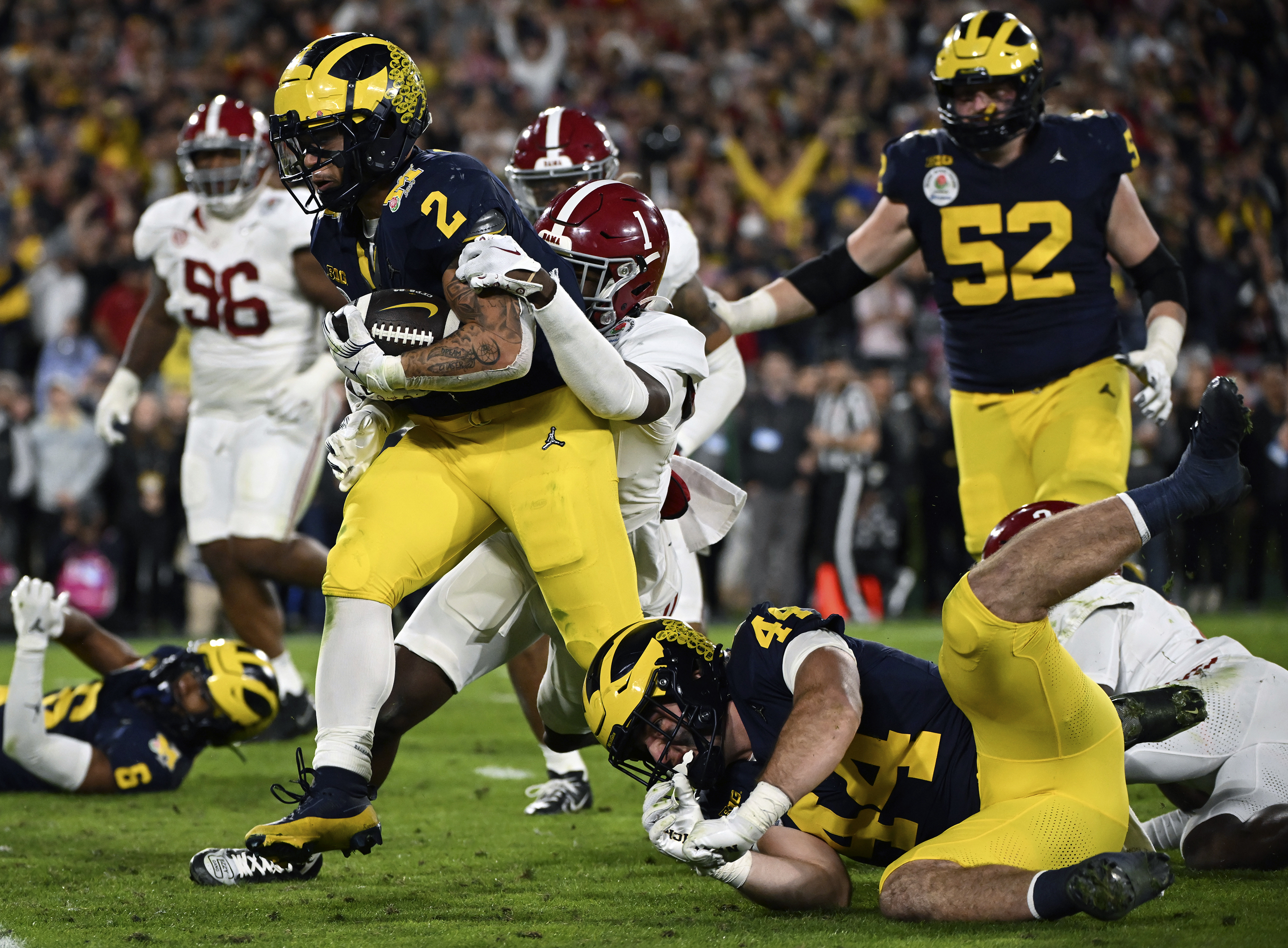 FILE - Michigan running back Blake Corum (2) runs in for a touchdown past Alabama defensive back Kool-Aid McKinstry (1) during overtime at the Rose Bowl CFP NCAA semifinal college football game Jan. 1, 2024, in Pasadena, Calif. Nonprofits Hail! Impact, which supports the University of Michigan's Wolverines, and Montlake Futures, which supports athletes at the University of Washington, are set to benefit regardless of who wins the national championship. 