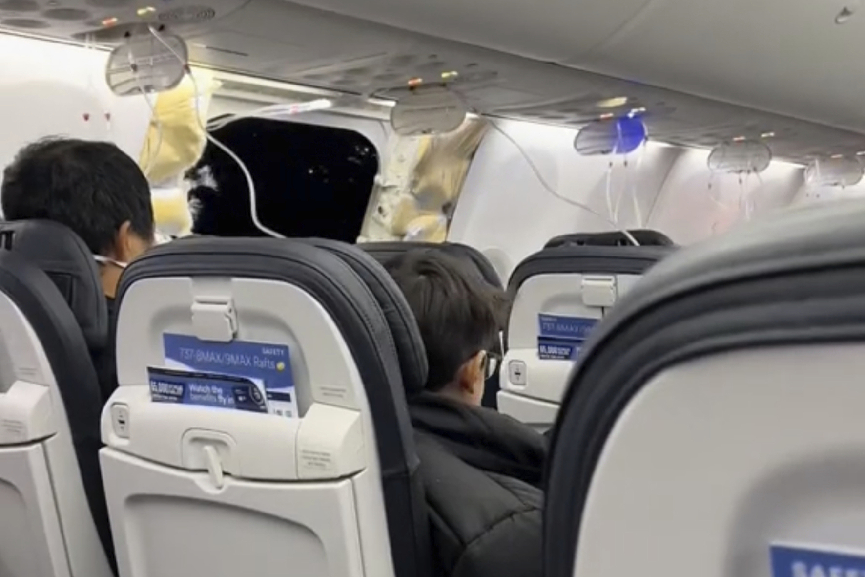 This image from video shows passengers near the damage on an Alaska Airlines Boeing 737 Max 9, Flight 1282, which was forced to return to Portland International Airport on Friday.